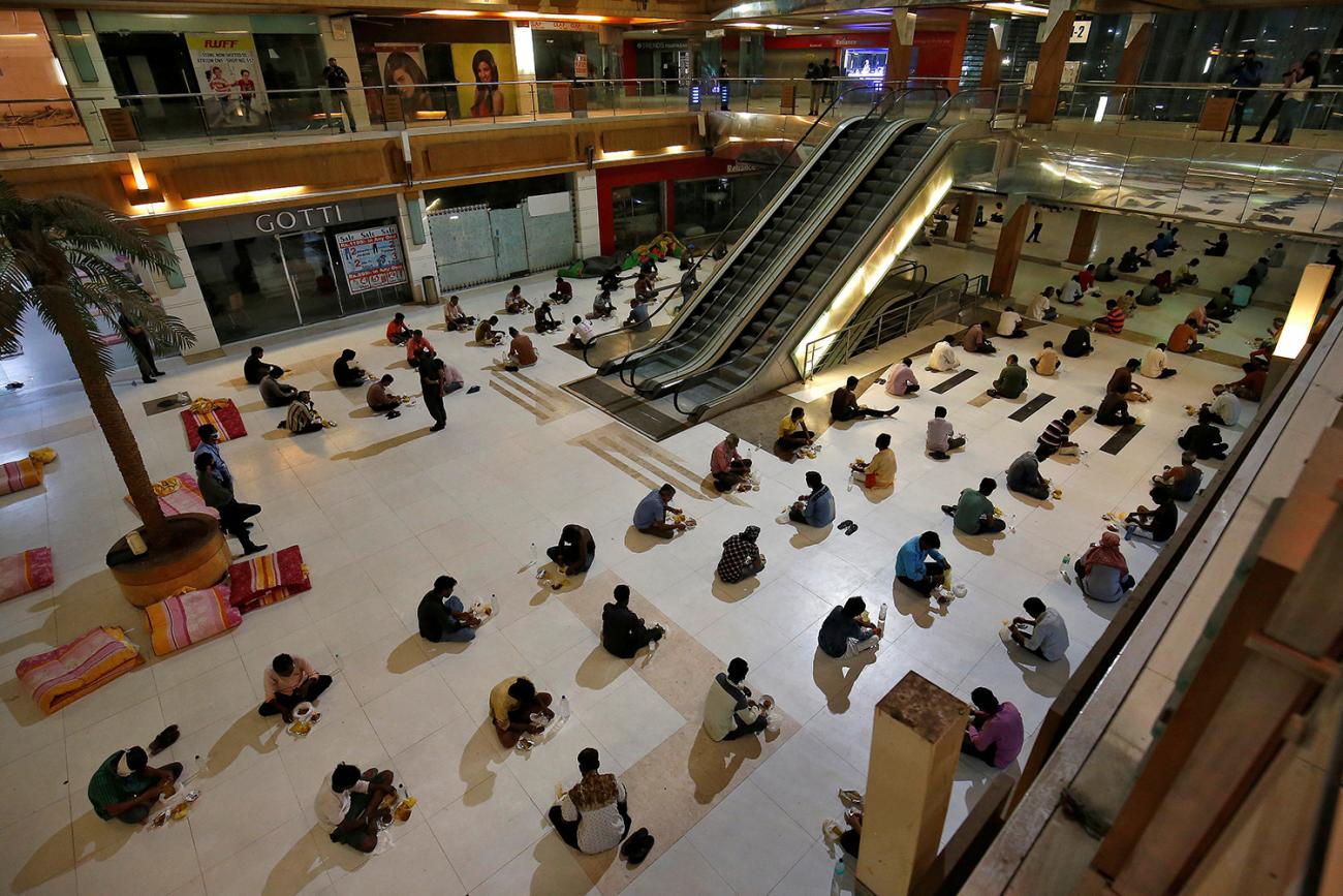The photo shows an interior section of shopping mall with dozens of people spaced out evenly on the lower level and stretching as far as the camera can show. 