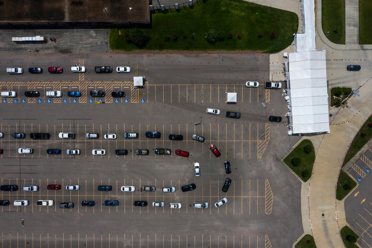The picture is an aerial photo of a large parking lot with cars snaking along in line. 