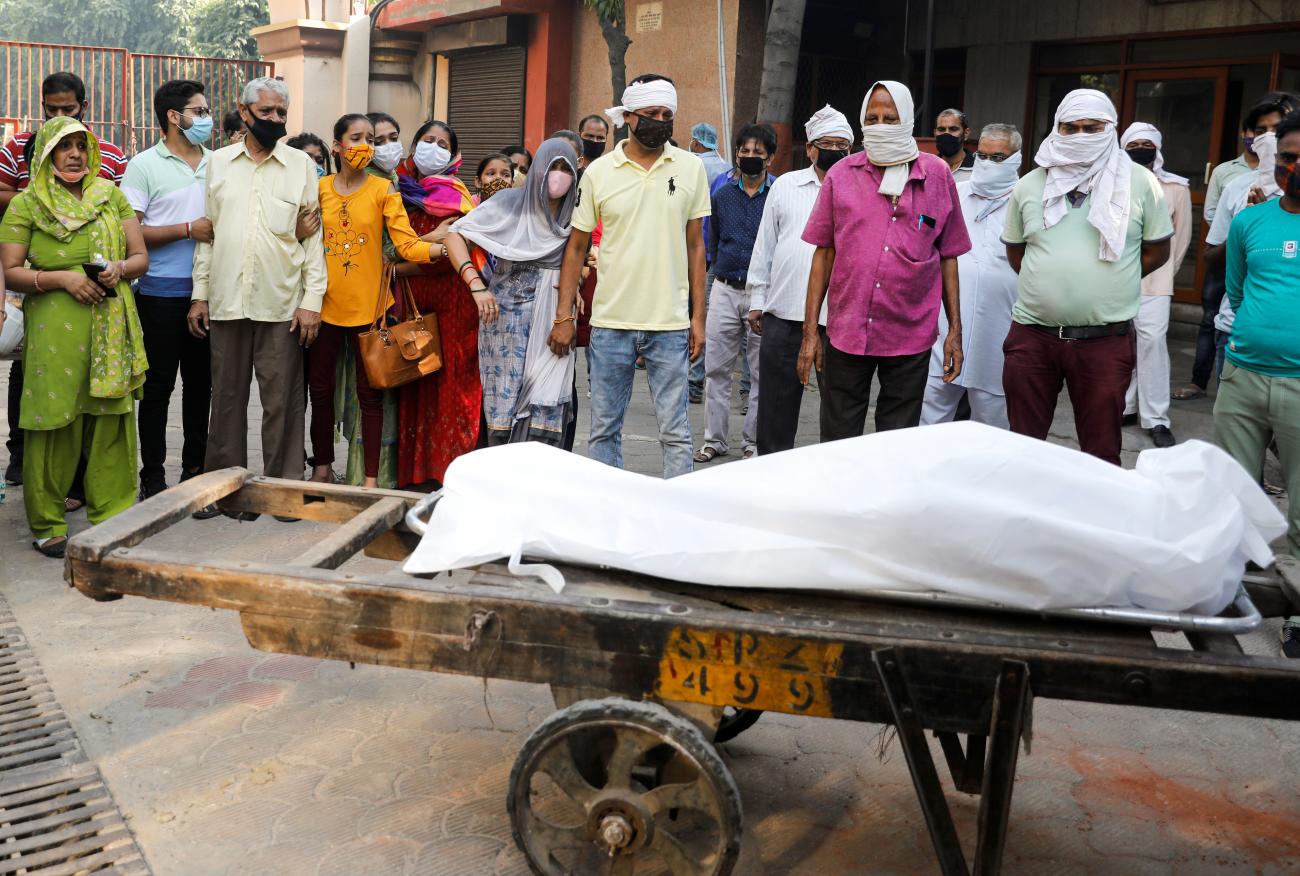 Relatives mourn as they stand next to the body of a man who died of COVID-19 before his cremation at a crematorium in New Delhi, India, September 28, 2020. 