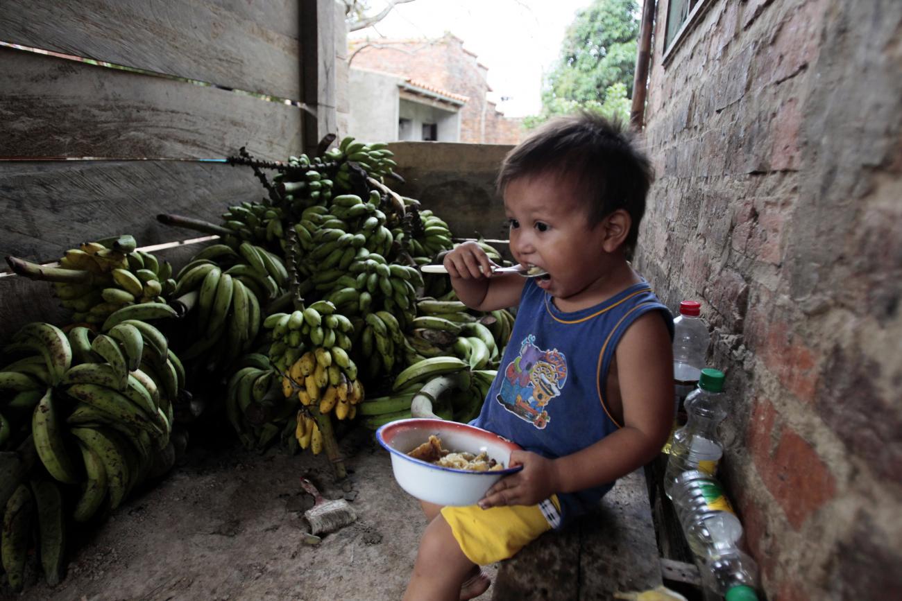 A boy feeds himself while sitting in front of a pile of bananas in the outskirts of Trinidad, a main city of Beni province in the Amazonic region of Bolivia April 25, 2012.