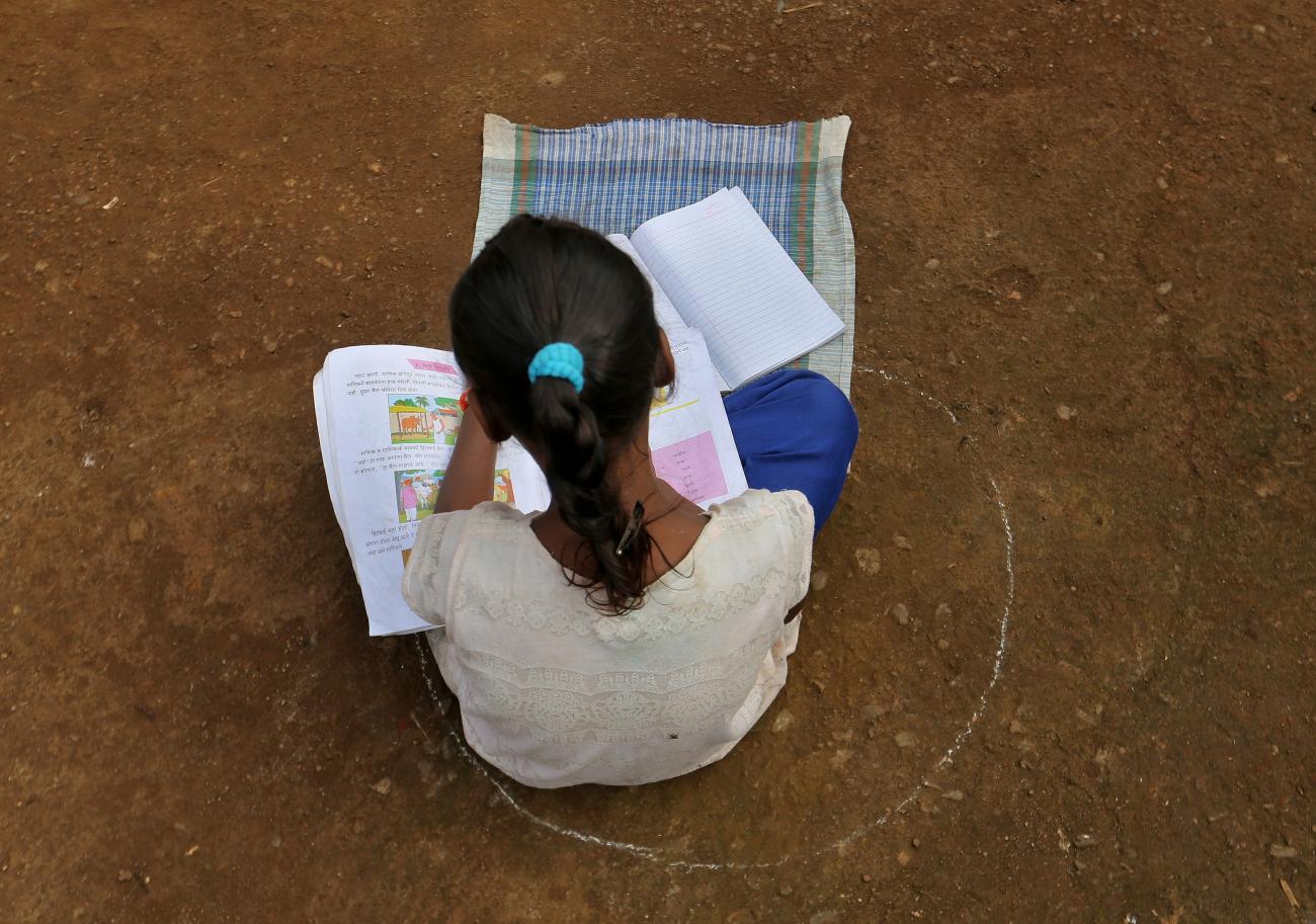 A girl, who has missed her online classes due to a lack of internet facilities, sits on the ground in a circle drawn with chalk to maintain safe distance as she listens to pre-recorded lessons over loudspeakers, after schools were closed following the coronavirus disease (COVID-19) outbreak, in Dandwal village in the western state of Maharashtra,