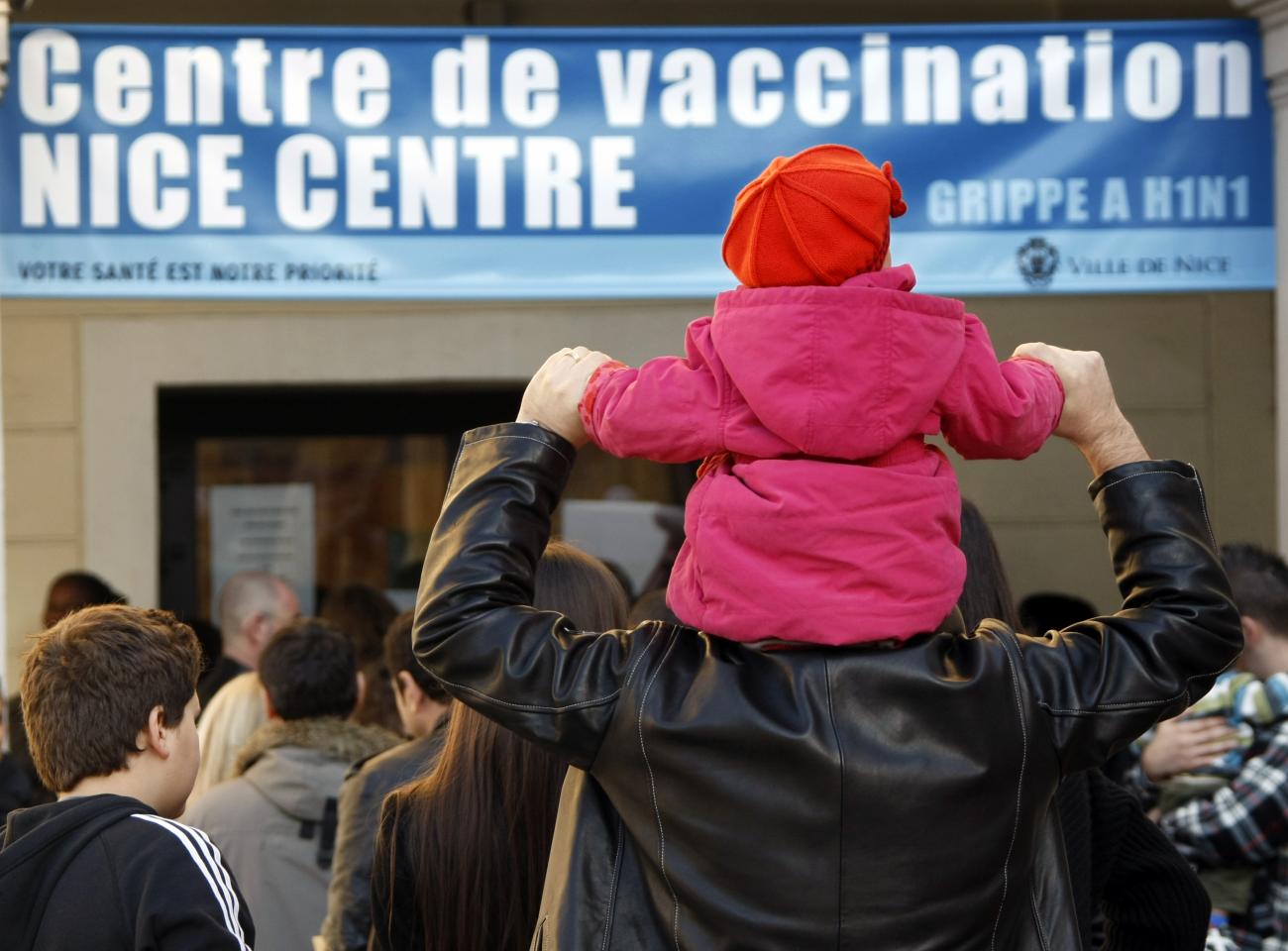 A little girl sits on the shoulders of a man as they stand in front of an H1N1 vaccination center in Nice, France, in 2009.