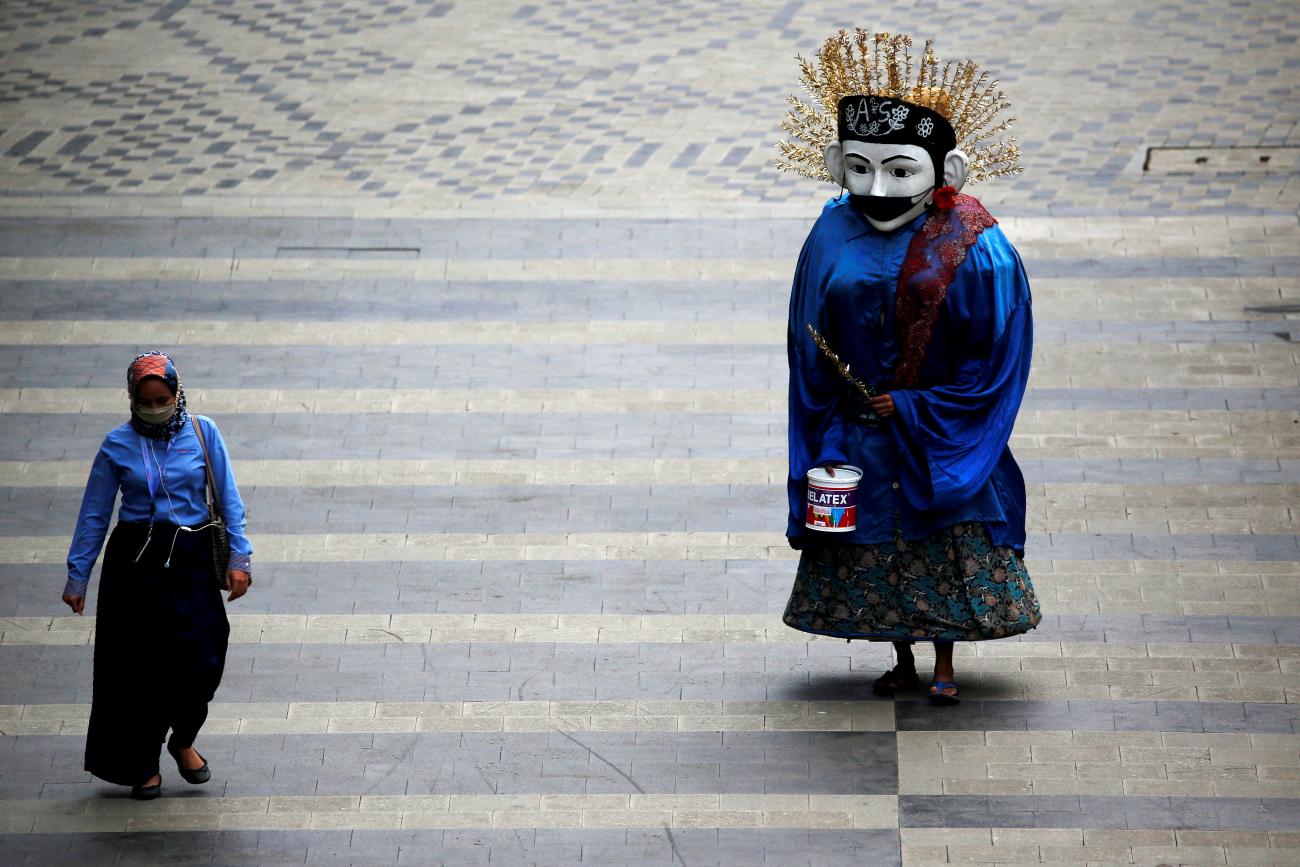 A traditional large puppet figure known as "Ondel-ondel", wearing a face mask, performs on a sidewalk of the main road, as the outbreak of the coronavirus disease (COVID-19) continues in Jakarta, Indonesia, January 4, 2021.