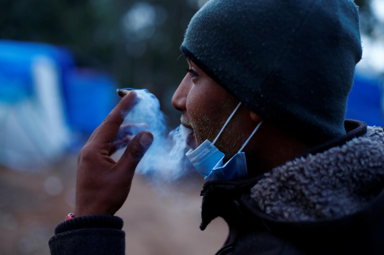 The profile of a man in a knit hat as he smokes a cigarette in the makeshift migrant camp in La Laguna, on the island of Tenerife, Spain, on March 26, 2021.
