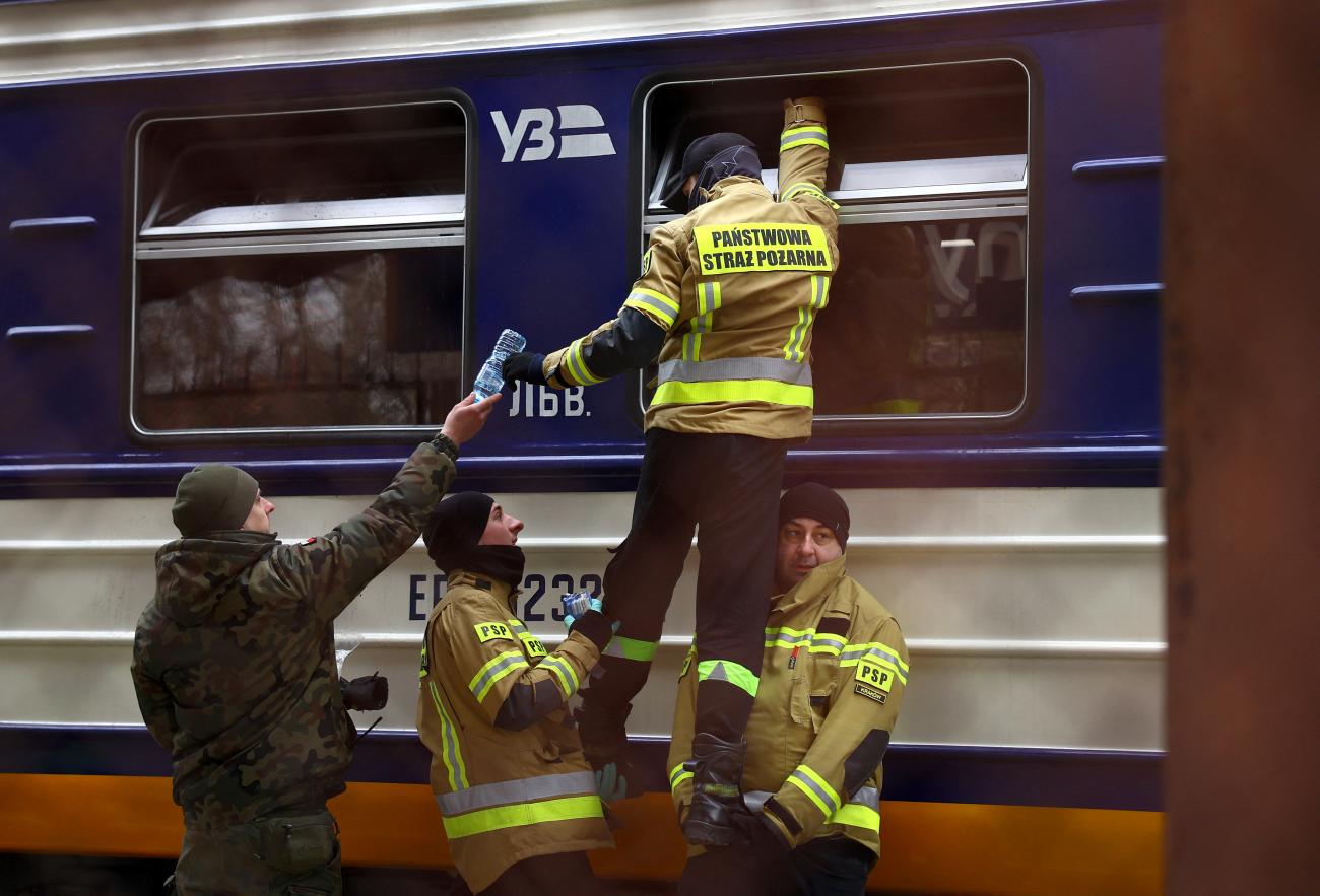 Firefighters hand water to people on a Ukrainian train who fled the Russian invasion, as they arrive at the train station in Przemysl, Poland, on March 2, 2022.