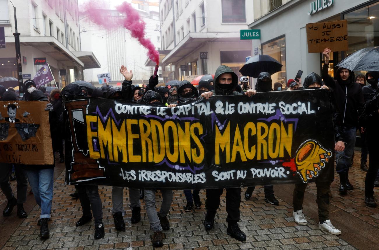 People hold a banner that reads "Piss off Macron" during a demonstration to protest against a bill that would transform France's current COVID-19 health pass into a "vaccine pass", in Nantes, France.