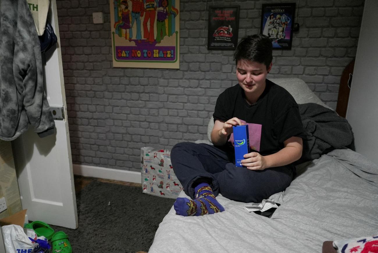 Miles Pitcher, 17, a transgender boy who told Reuters how he had turned to an online provider for private gender care after waiting years for the UK’s National Health Service (NHS) to deliver it, opens a box of Testogel testosterone gel as he poses for a photo in his room in Dover, Britain, November 28, 2022.