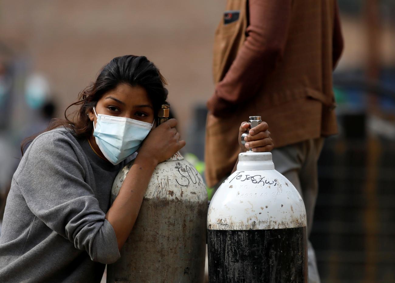 A woman holds on to the oxygen cylinders for a patient after refilling them at a factory amid the spread of coronavirus disease (COVID-19) surge as India's outbreak spreads across South Asia, in Kathmandu, Nepal, on May 9, 2021.