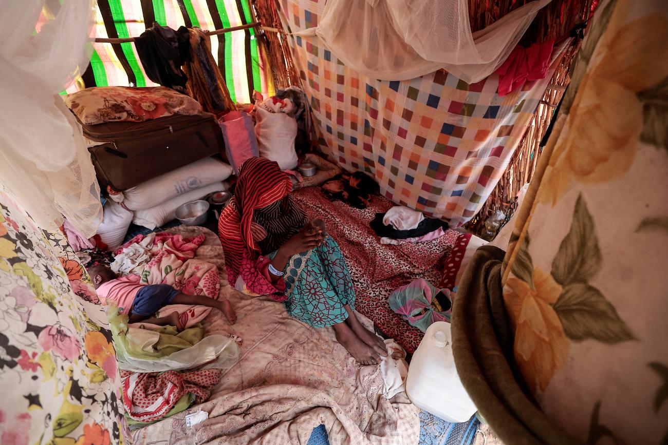 A 24-year-old mother, who said she became pregnant after two gunmen assaulted her, in El Geneina, West Darfur, poses next to her toddler inside a makeshift shelter.