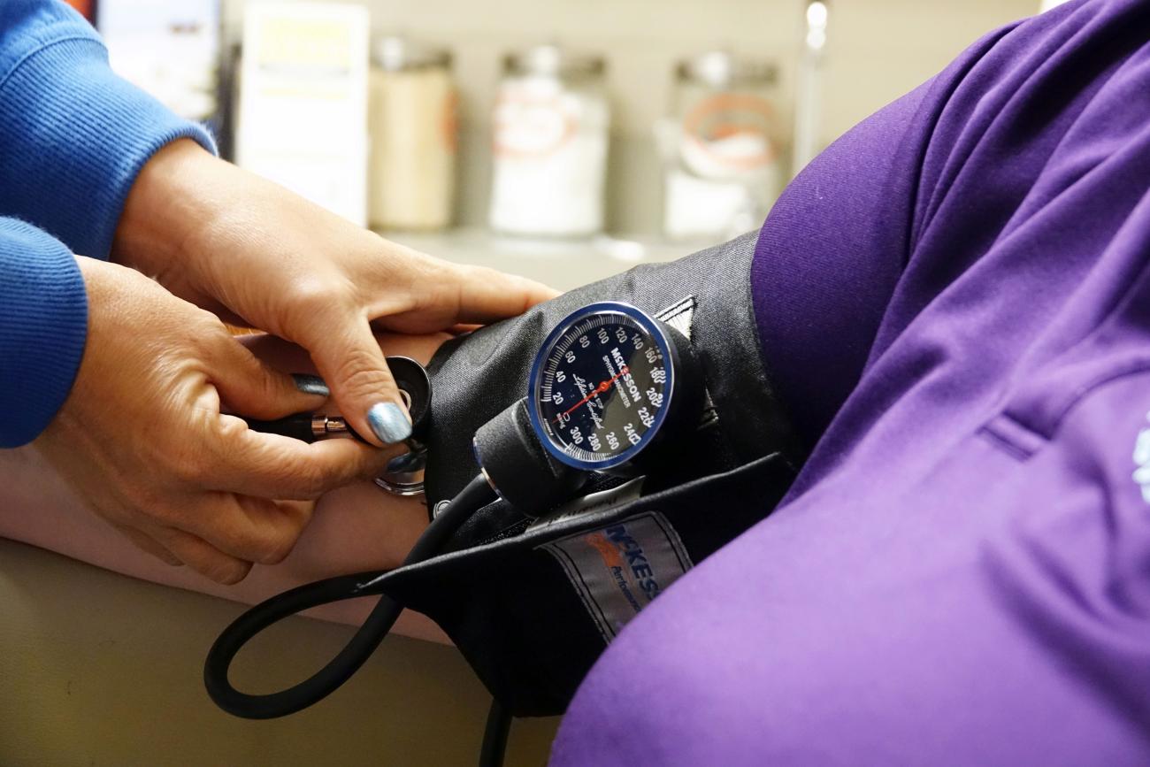 A nurse takes someones blood pressure.