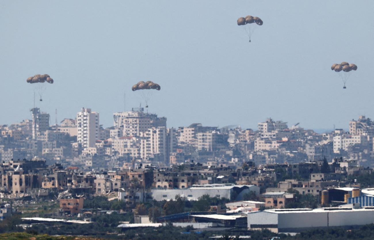 Humanitarian aid falls through the sky towards the Gaza Strip after being dropped from an aircraft.