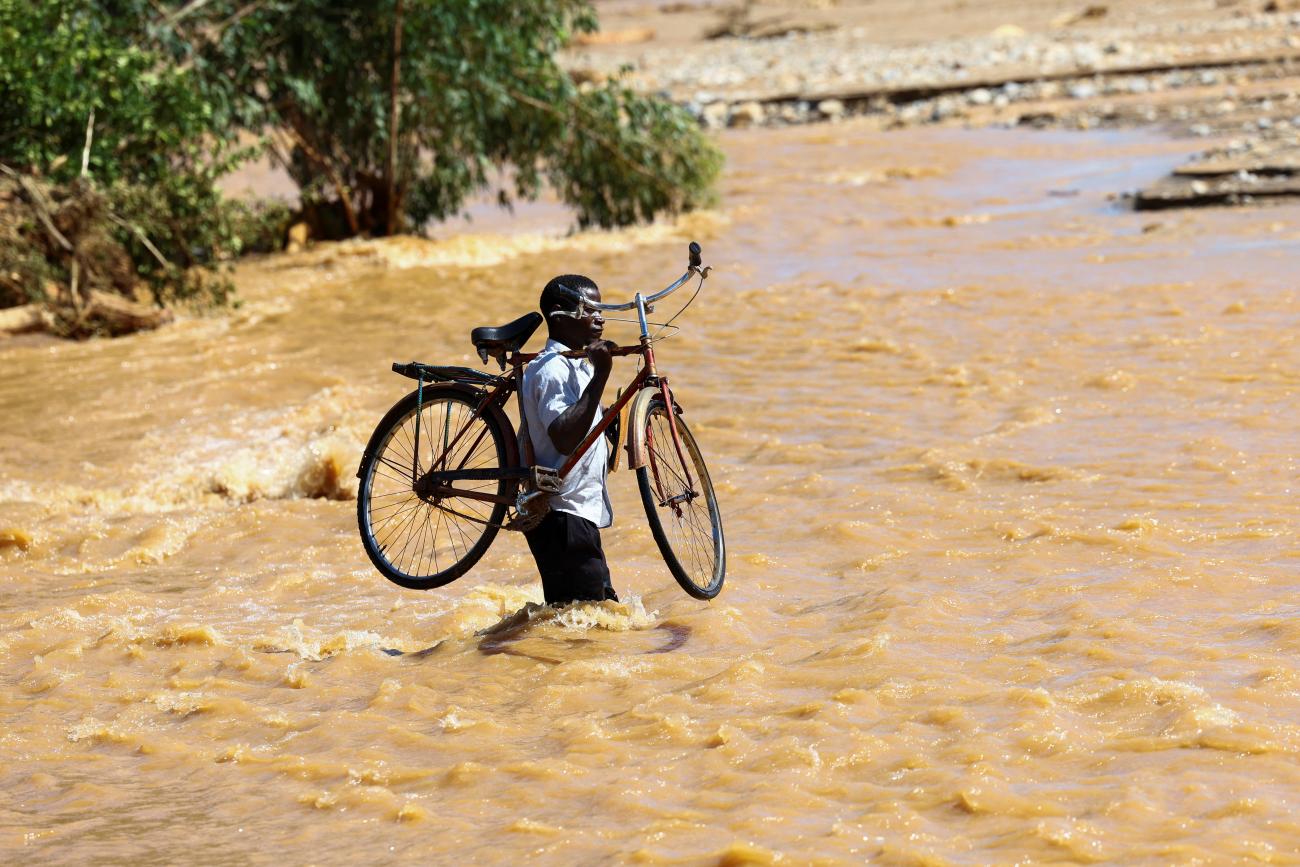 A man carries his bicycle over a flooded area in Muloza after the tropical Cyclone Freddy.