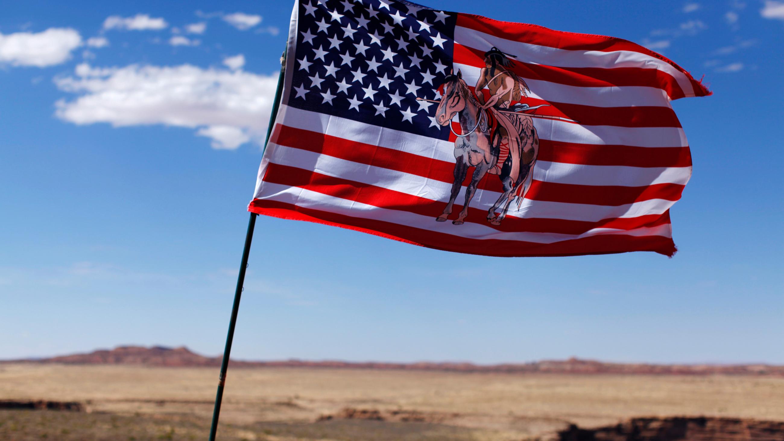 The photo shows a flag blowing in the wind with an Indian horse rider on the flag. 