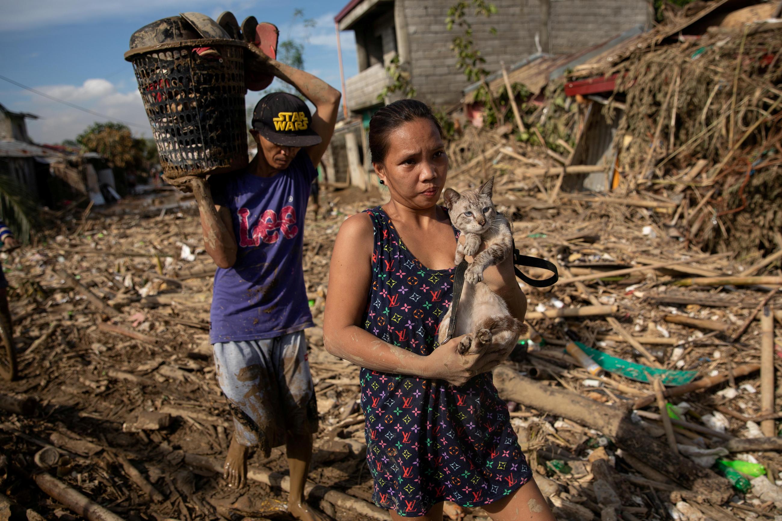 A woman retrieves her cat from a submerged village following floods caused by Typhoon Vamco, in Rodriguez, Rizal province, Philippines, November 14, 2020.