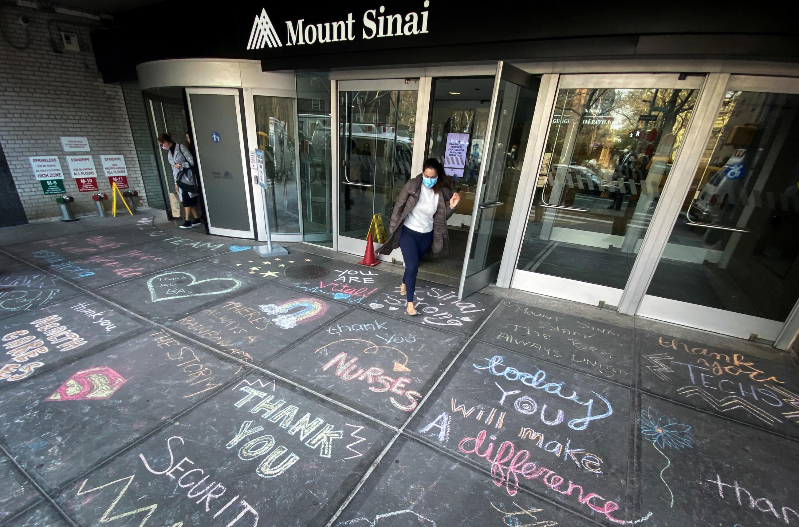 A woman exits Mount Sinai Hospital in Manhattan past messages of thanks written on the sidewalk during the outbreak of the coronavirus disease (COVID19) in New York City, New York, U.S., April 7, 2020. 