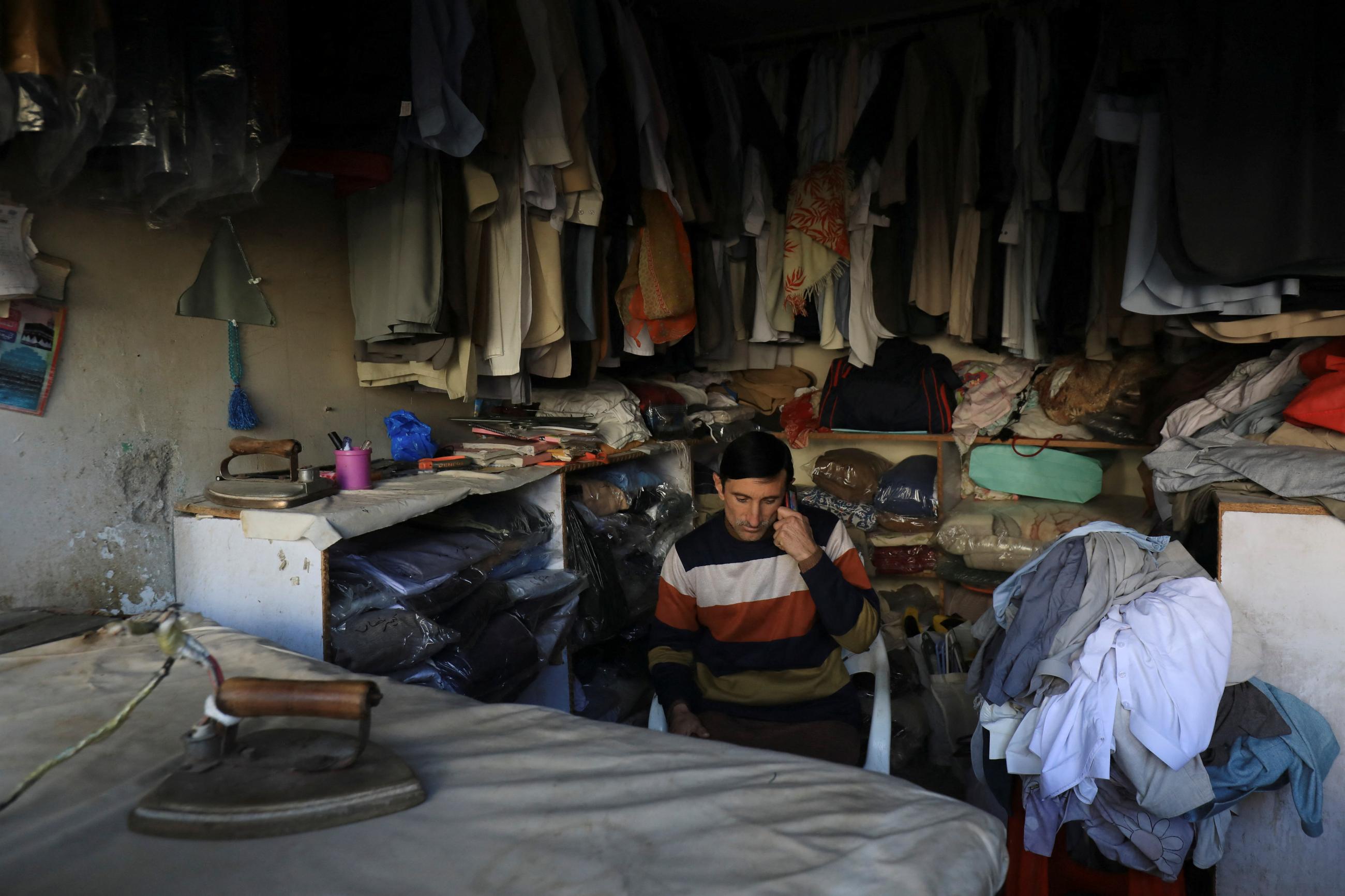 A laundryman uses cell phone as he sits at his shop during countrywide power breakdown in Peshawar, Pakistan, on January 23, 2023. REUTERS/Fayaz Aziz