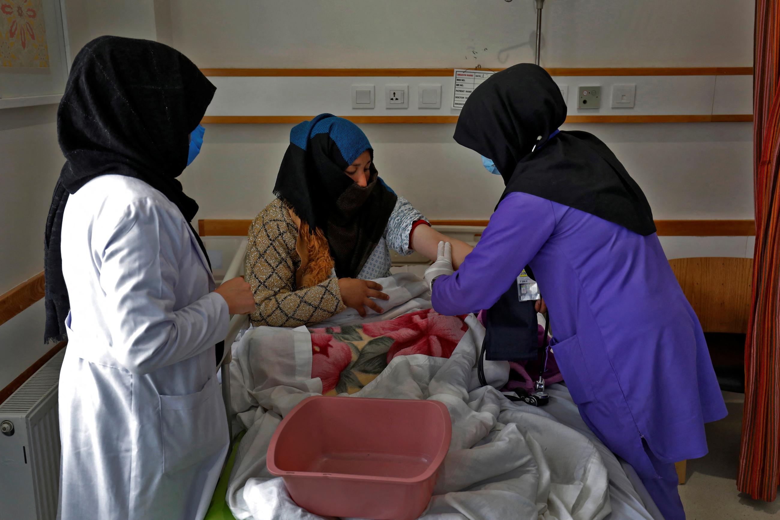 A trainee midwife examines a woman at a hospital.