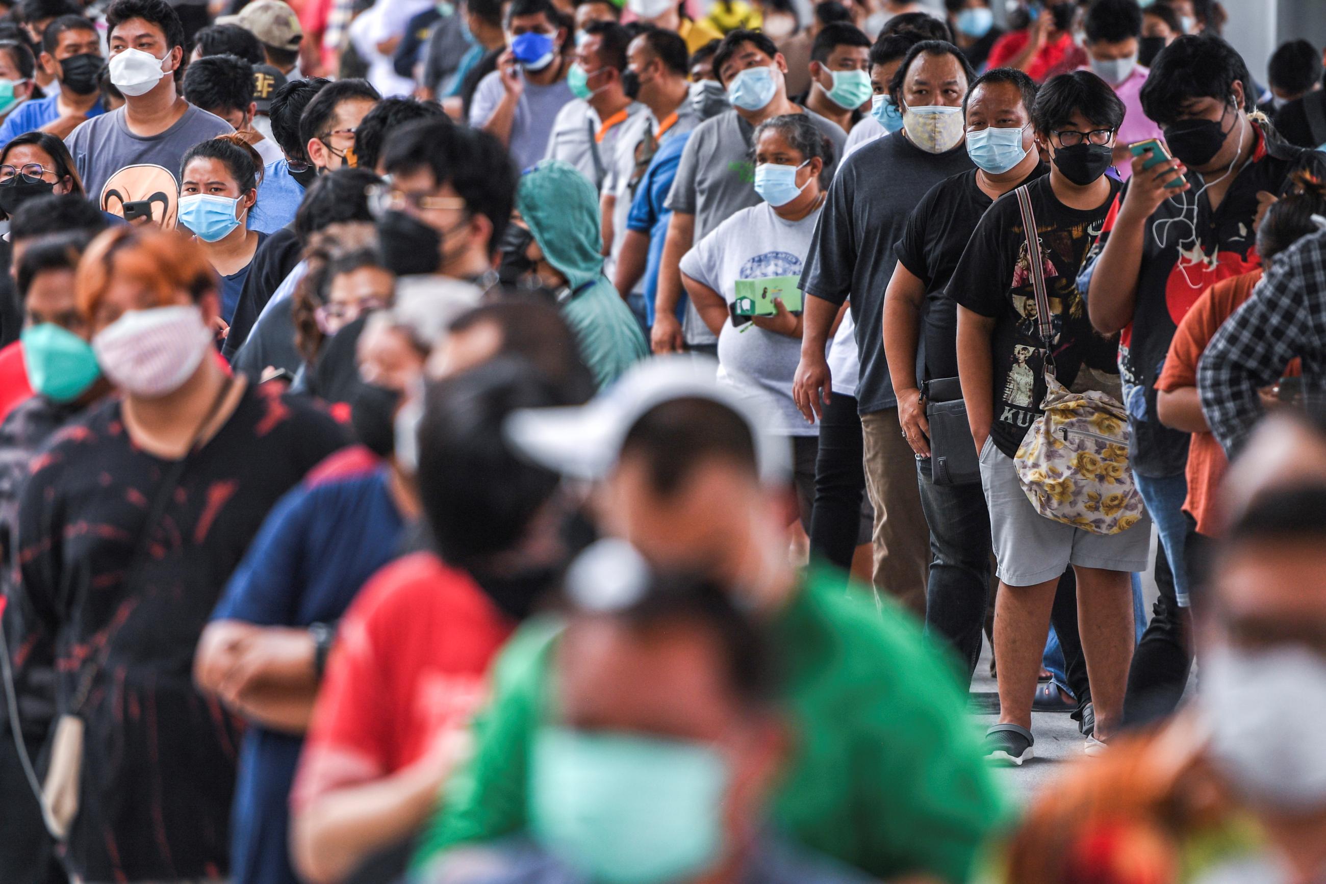 People wearing protective masks queue outside the Central Vaccination Center.