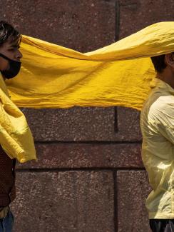 The image shows two men sharing a yellow scarf. 