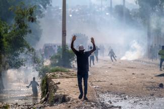A man raises his hands after the Haitian National police deployed tear gas to disperse the crowd during a protest demanding the resignation of Prime Minister Ariel Henry, in Port-au-Prince, Haiti. 