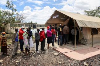 People stand in line to receive a COVID-19 vaccine, at the Narok County Referral Hospital.