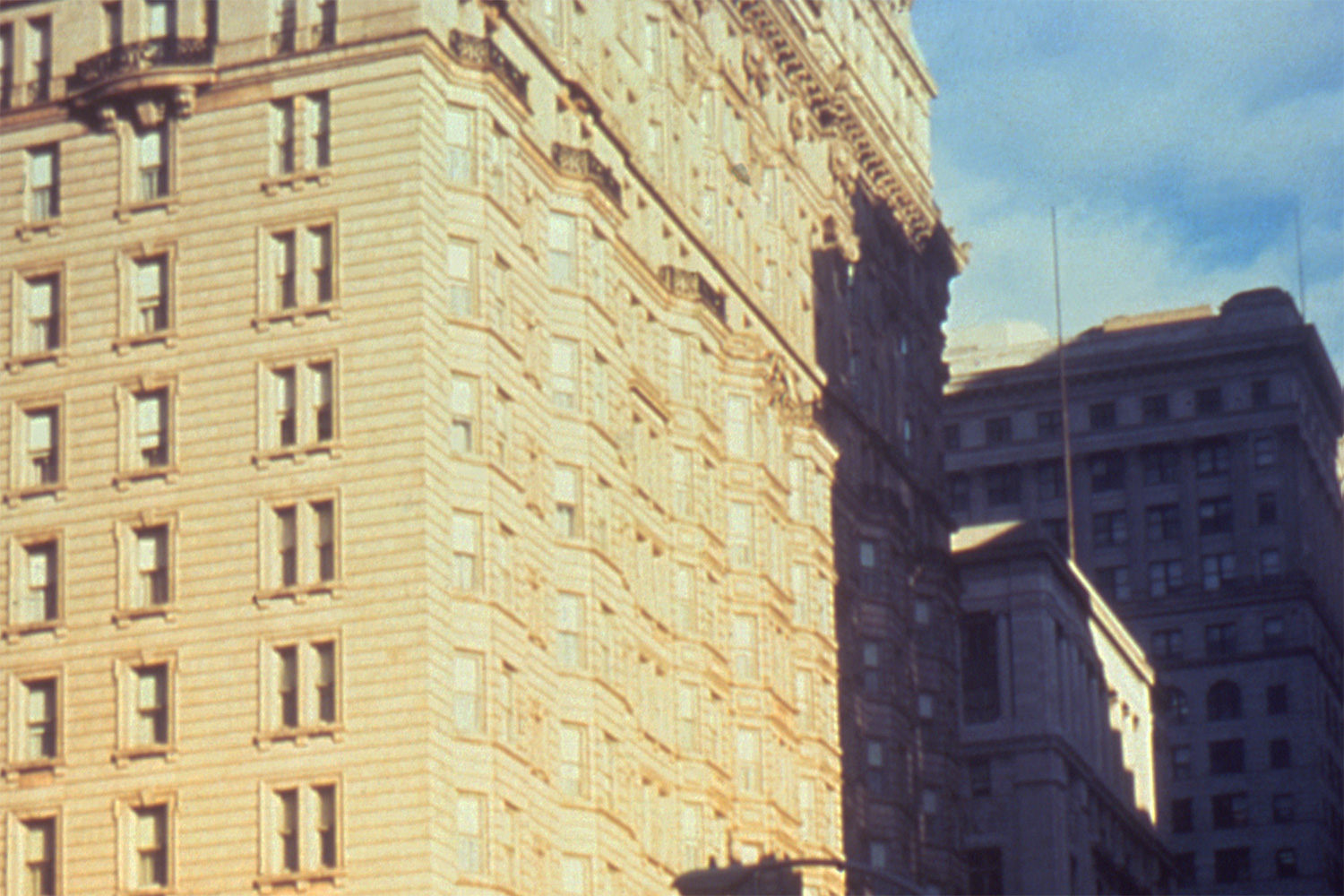 The photo shows an old, magnificent stone building against a bright blue sky. It’s a grainy photo, suggestive of a poor quality color film stock or a cheap camera.