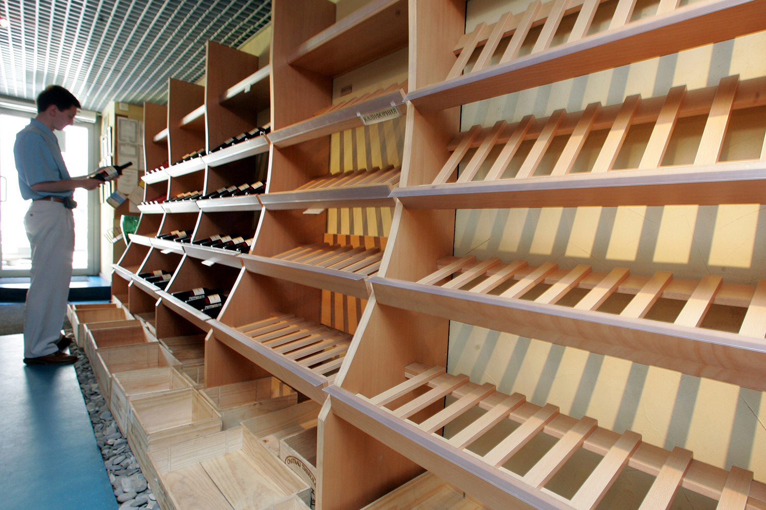The image shows the shopkeeper in front of nearly empty shelves.