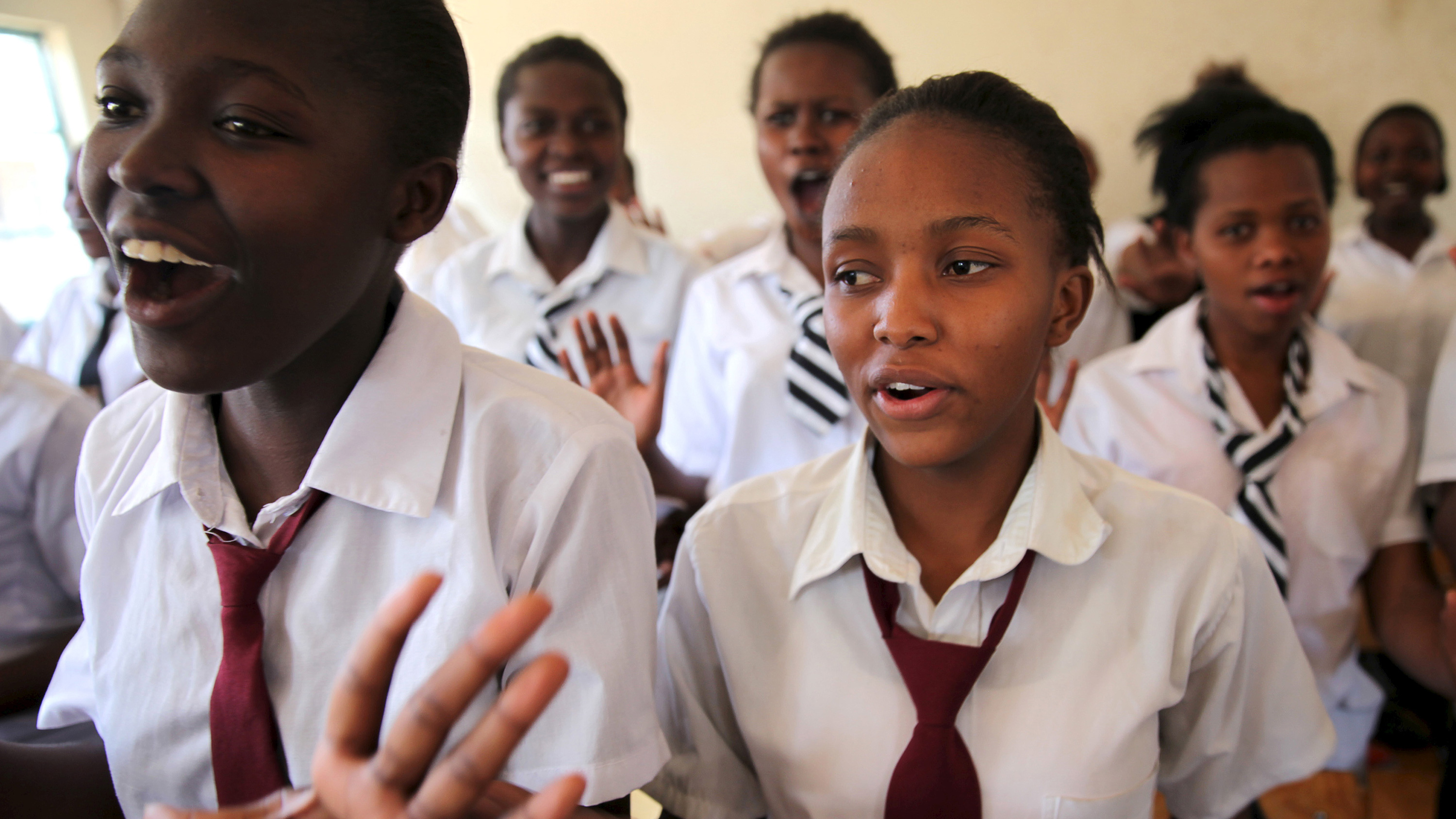 The girls are standing and gesturing with their hands and speaking out loud.