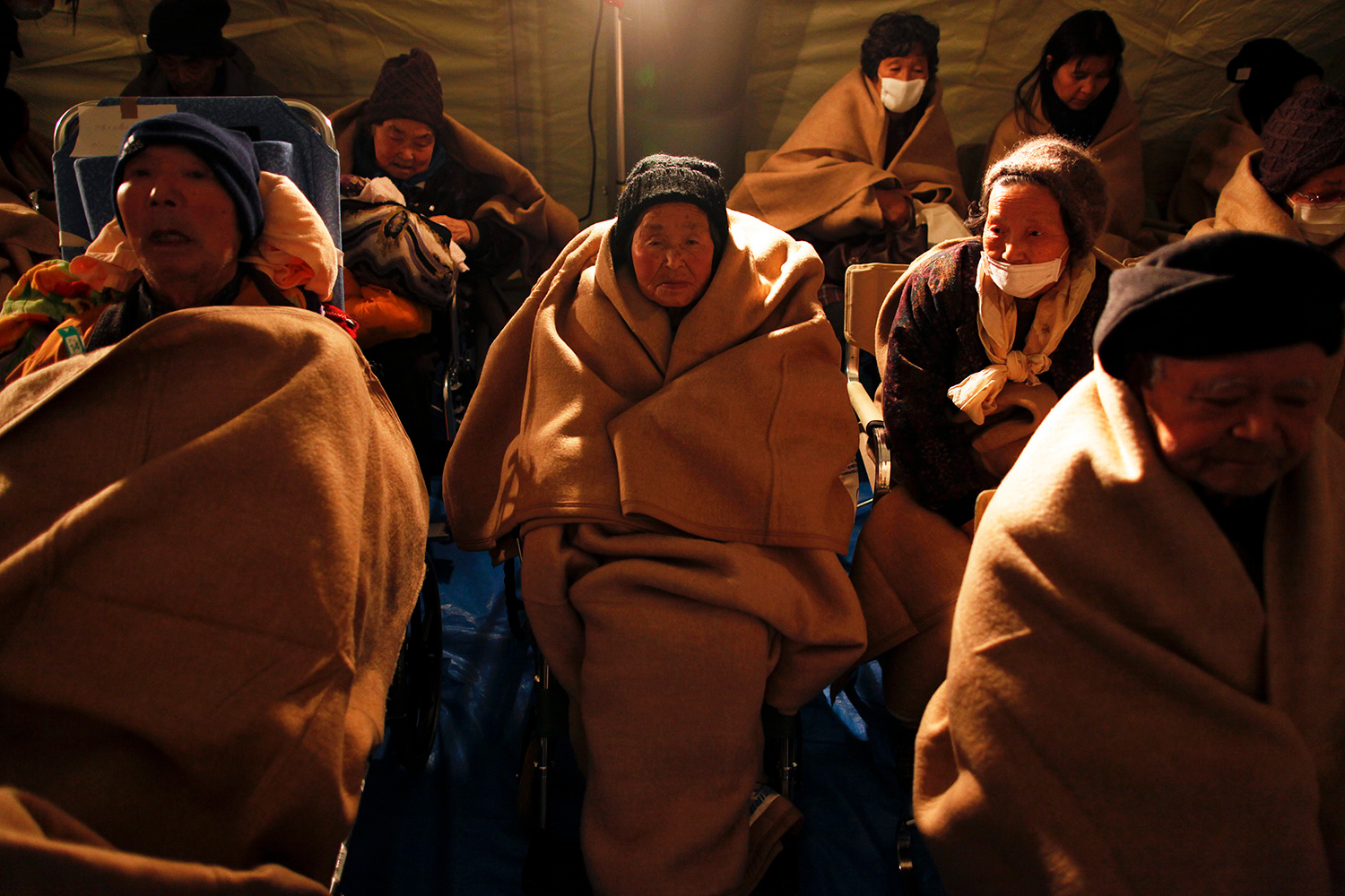 Photo shows a half dozen people all wrapping themselves in generously sized fluffy brown blankets.