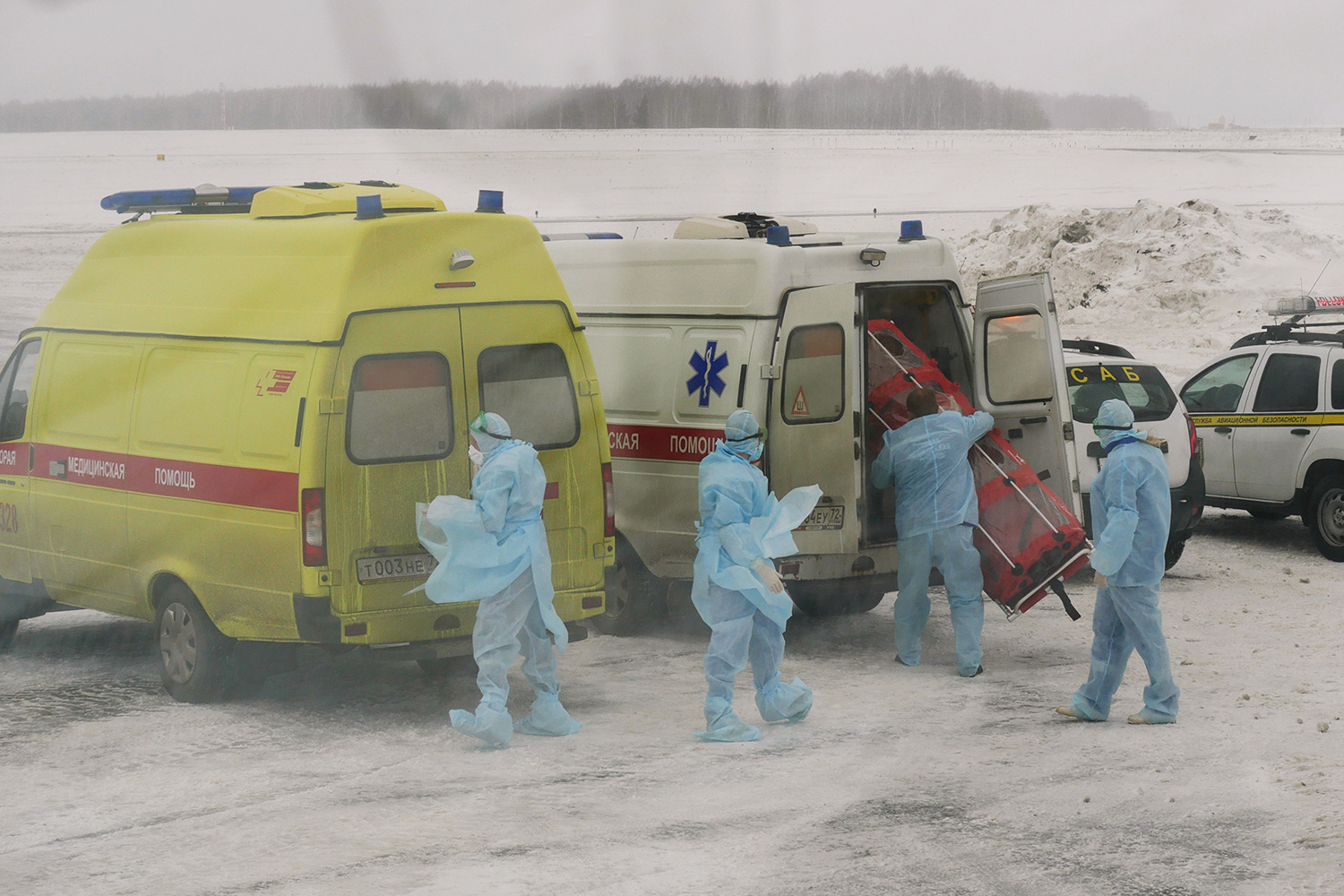 The photo shows several workers in blue protective suits standing outside their ambulances in what appears to be freezing weather.