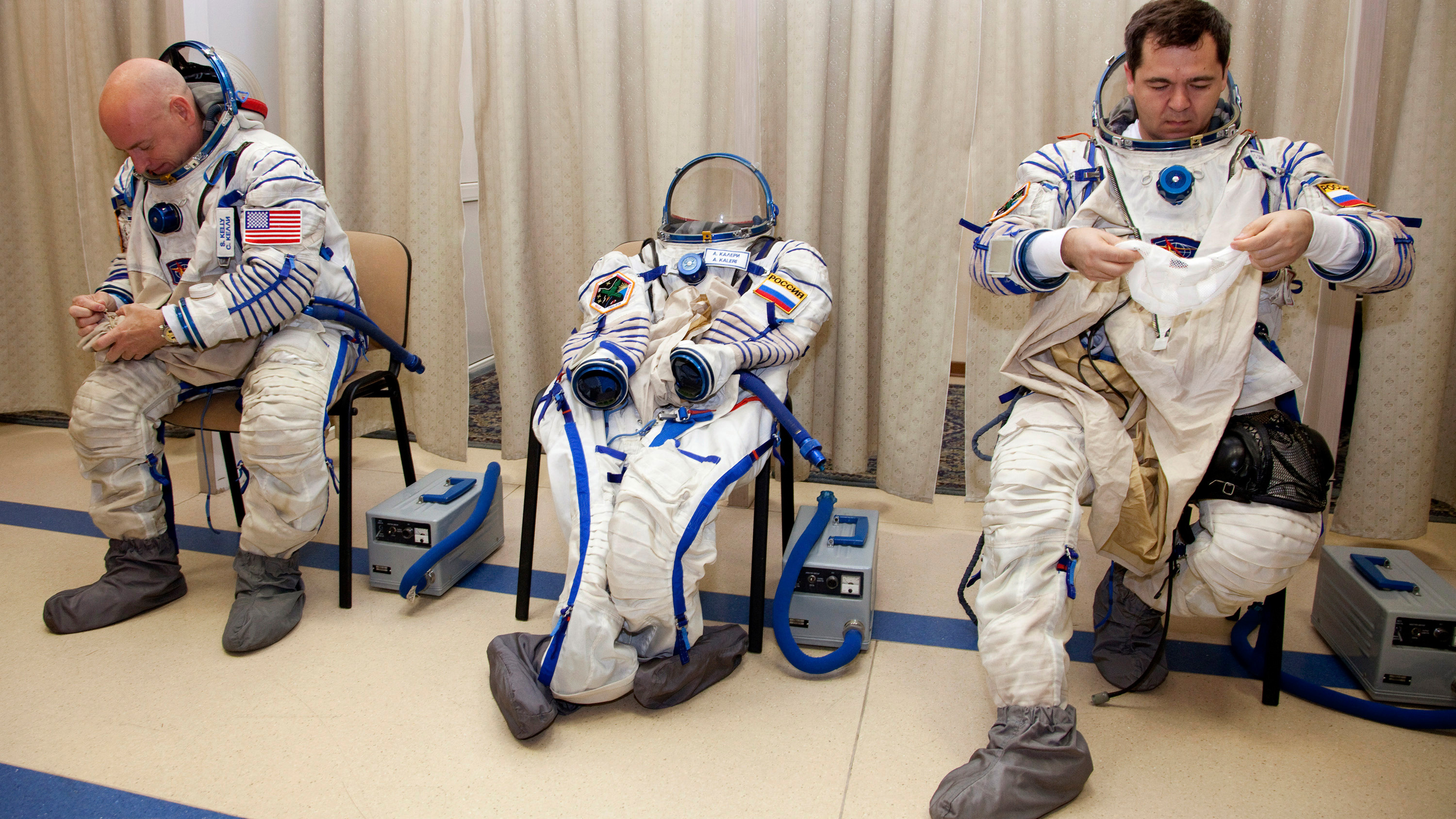 The photo shows the two space travelers donning their classic full-body space suits. In between them is a third suit that lies empty.