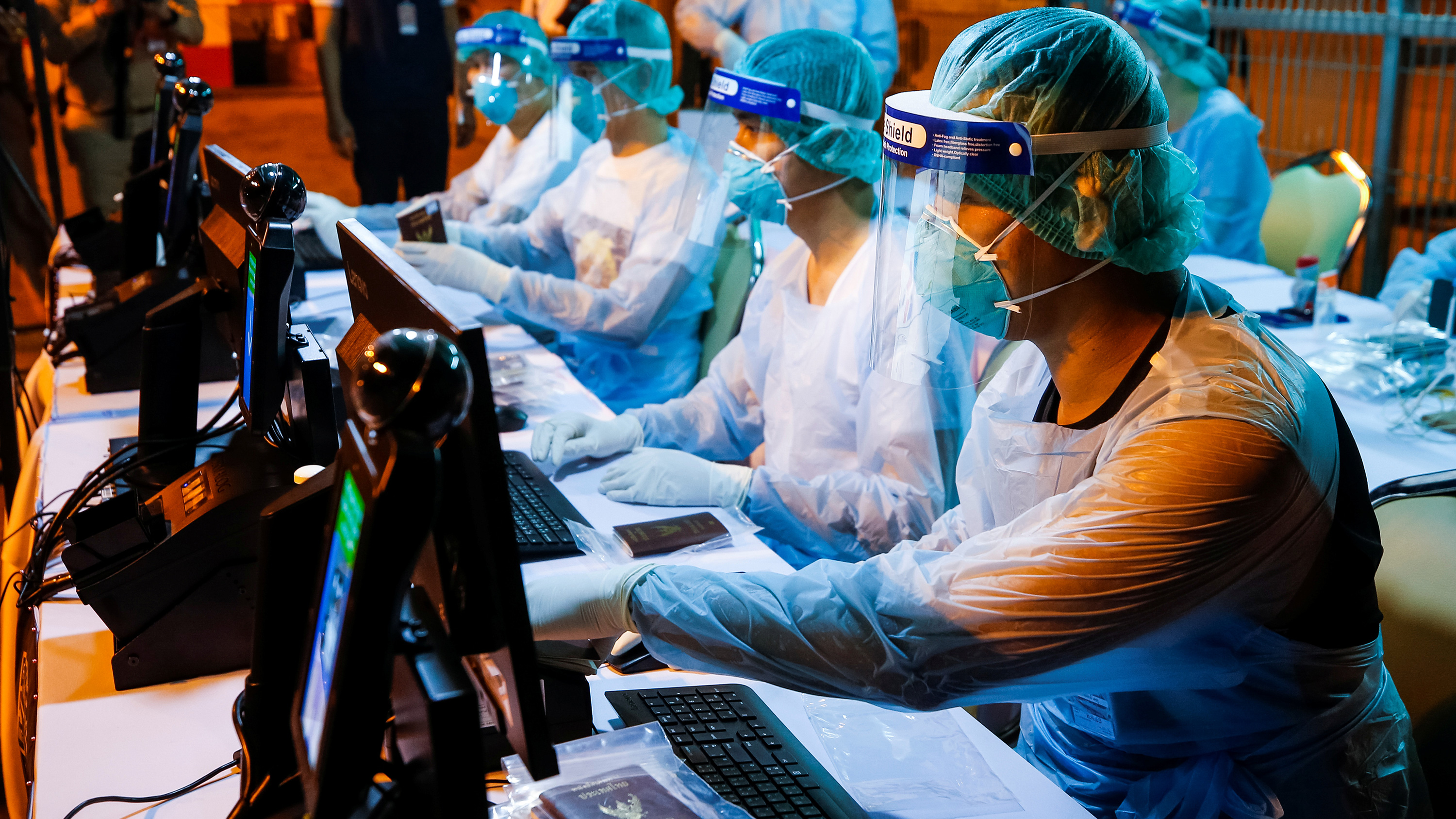 Photo shows workers art computers, and they are completely clad in protective gear.