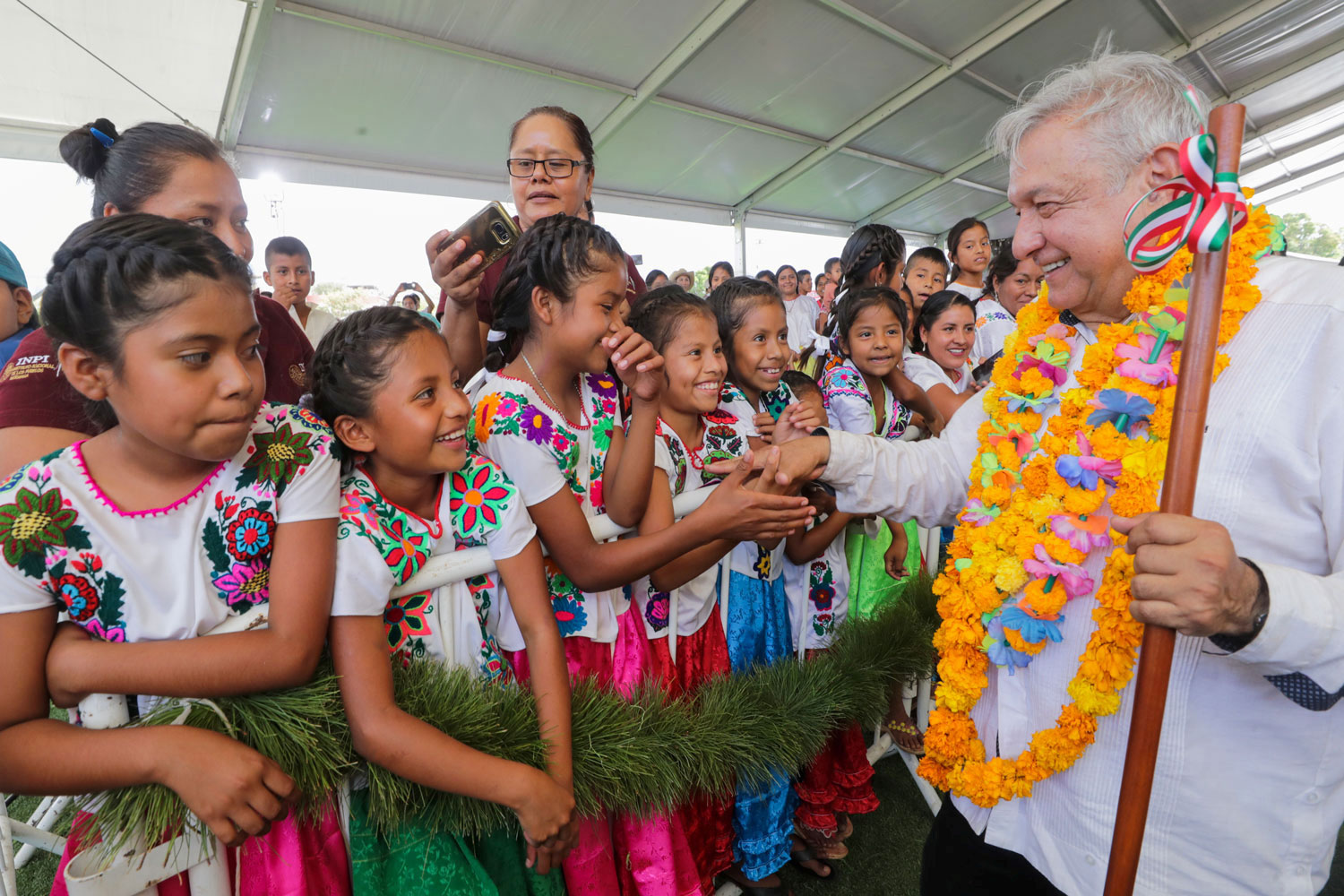 The photo shows the president smiling broadly as he moves down a receiving line of young girls who are also smiling gleefully and reaching out to shake his hand.