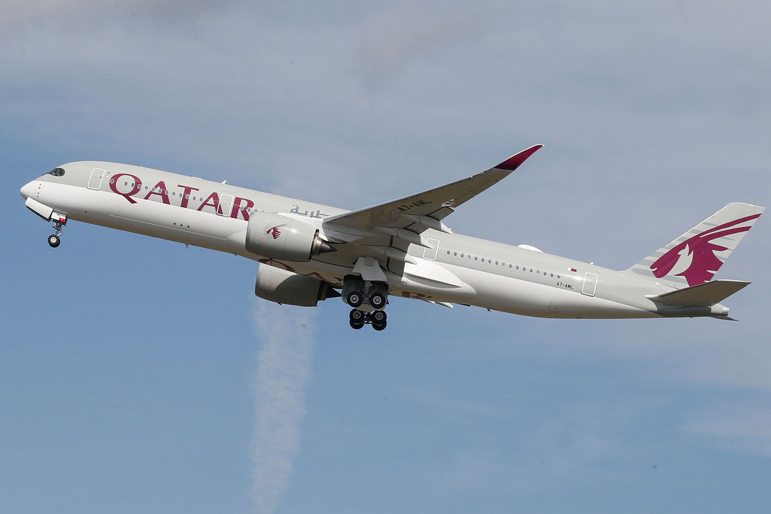 The photo shows a Qatar Airways jetliner in takeoff against a bright blue sky.