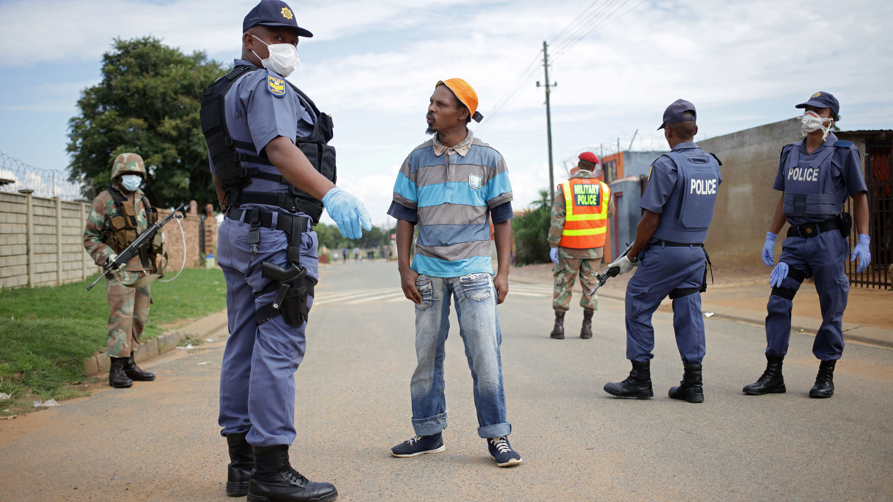 The photo shows several uniformed officers carrying guns. One is talking to the resident who was stopped.
