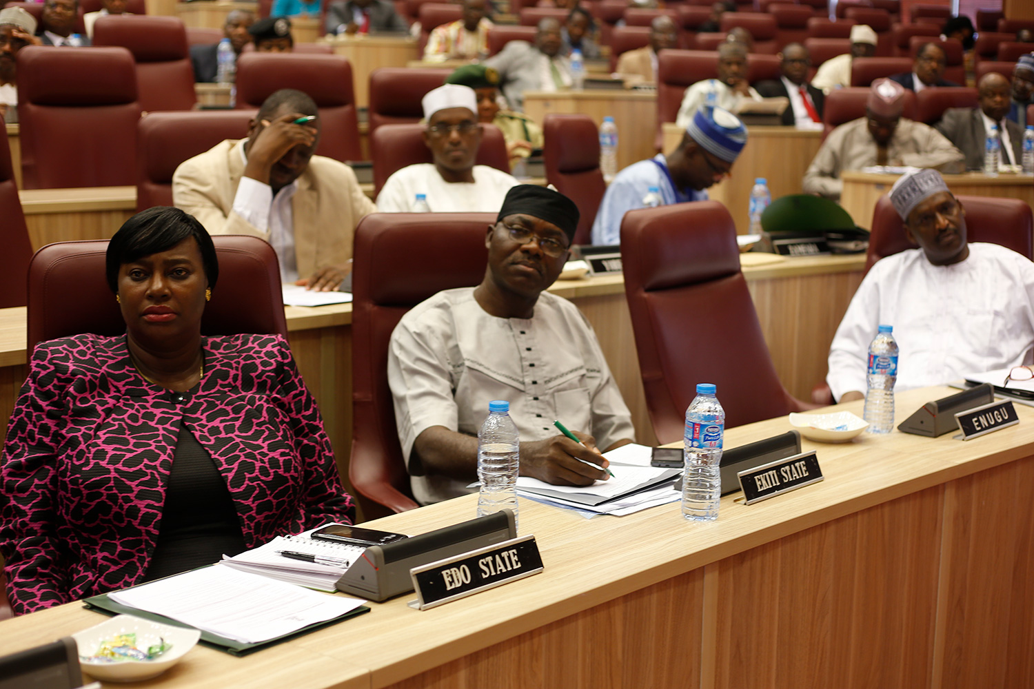 The picture shows several rows of people sitting and listening attentively in a stately lecture hall. 