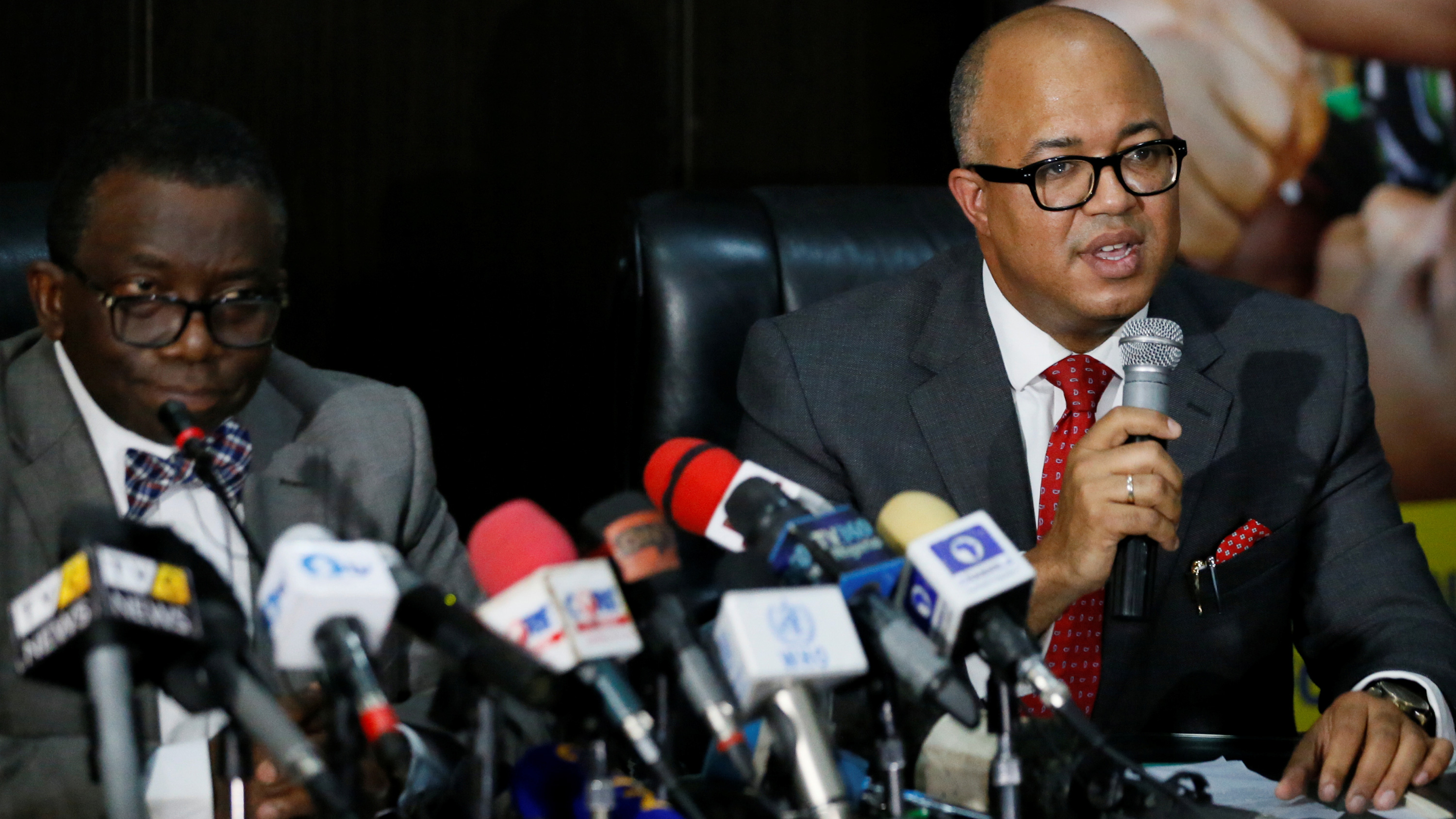 The picture shows the health minister at a press conference speaking into a microphone.
