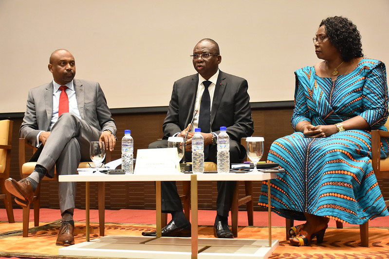 The image shows the three former ministers witting in lounge chairs having a panel discussion on a stage.