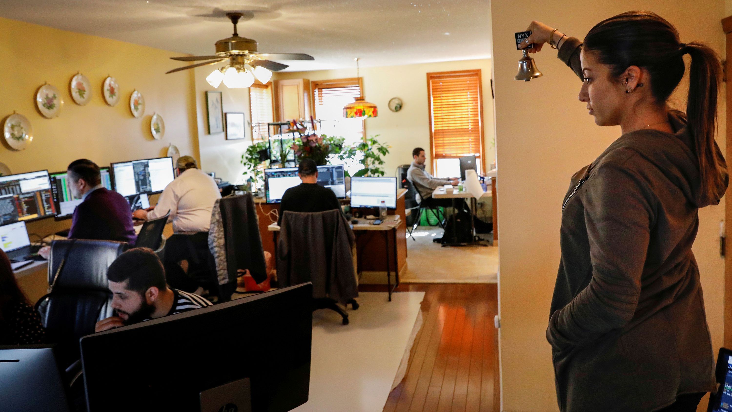 Image shows a room in what appears to be a row house converted into an office with a woman on one end ringing a tiny bell.