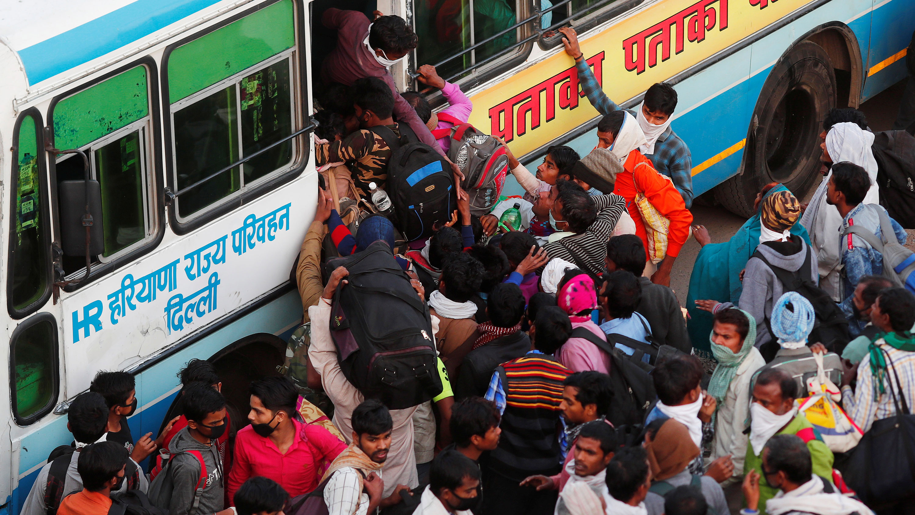 The image shows a huge crowd clamoring to board a bus.