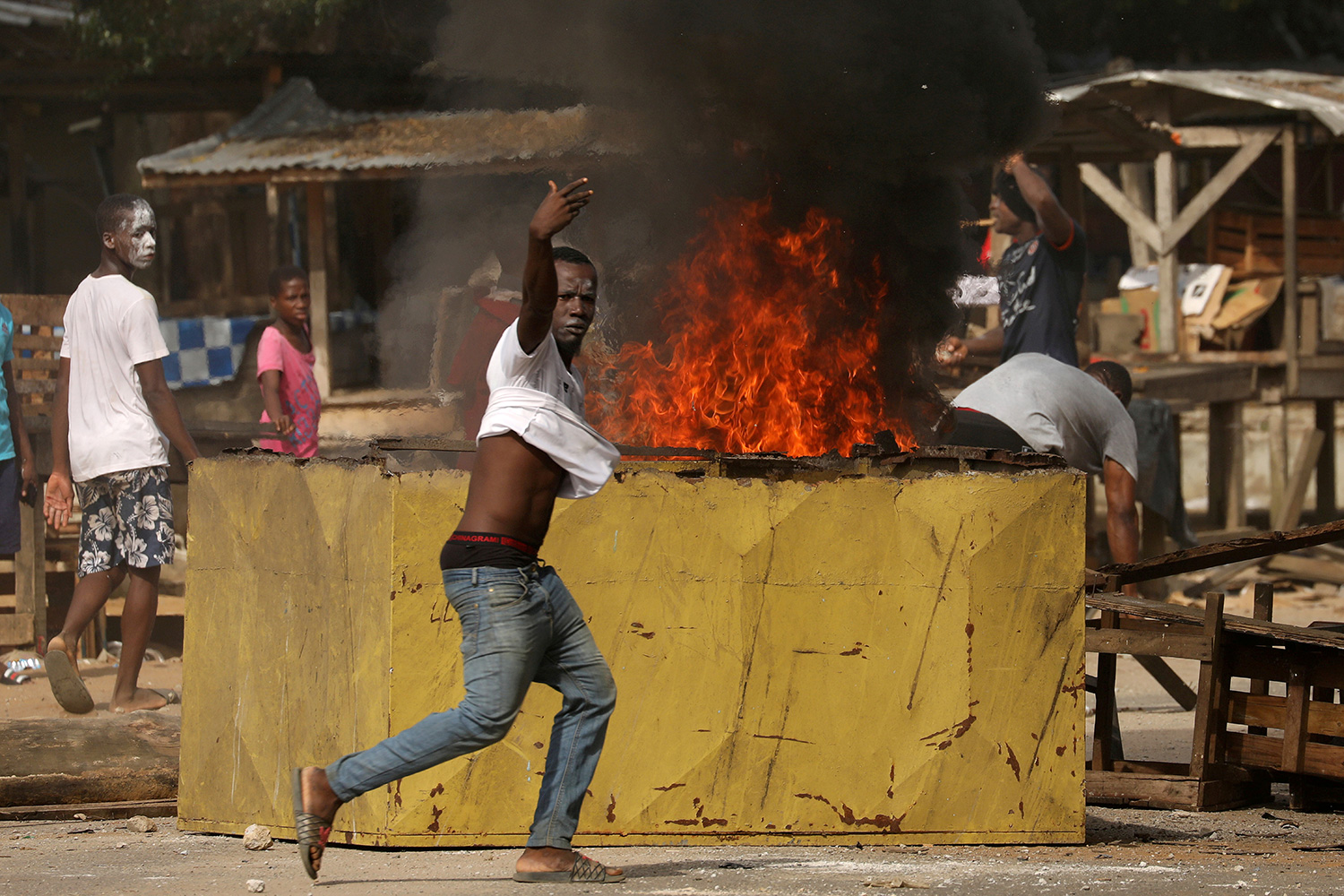 This is a powerful photo showing a protester shouting at the camera as fires rage in the background.