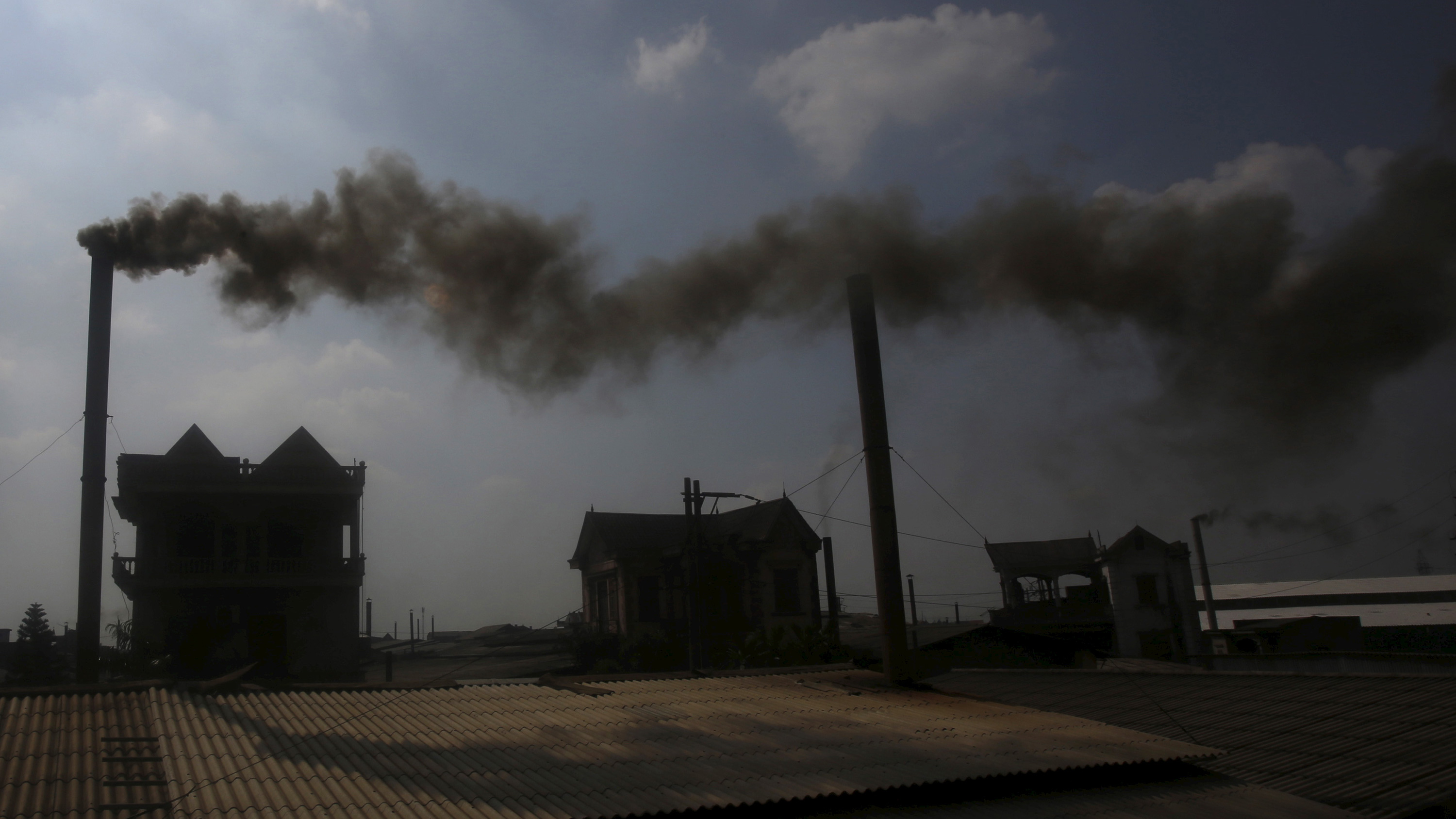 The photo shows the silhouette of a factory in the distance belching smoke.