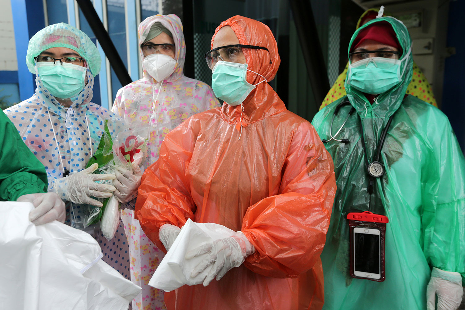 Picture shows a number of health workers wearing thin rain coats instead of protective gowns.