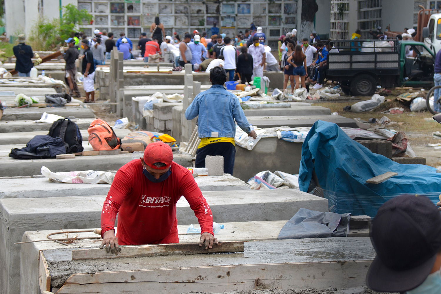 The photo shows a large area with many workers constructing caskets.