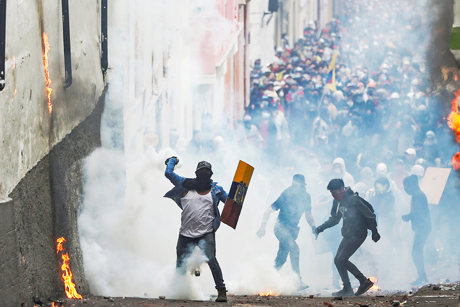 This is a powerful image with a street of protestors and one of them throwing back a canister in the direction of the camera.