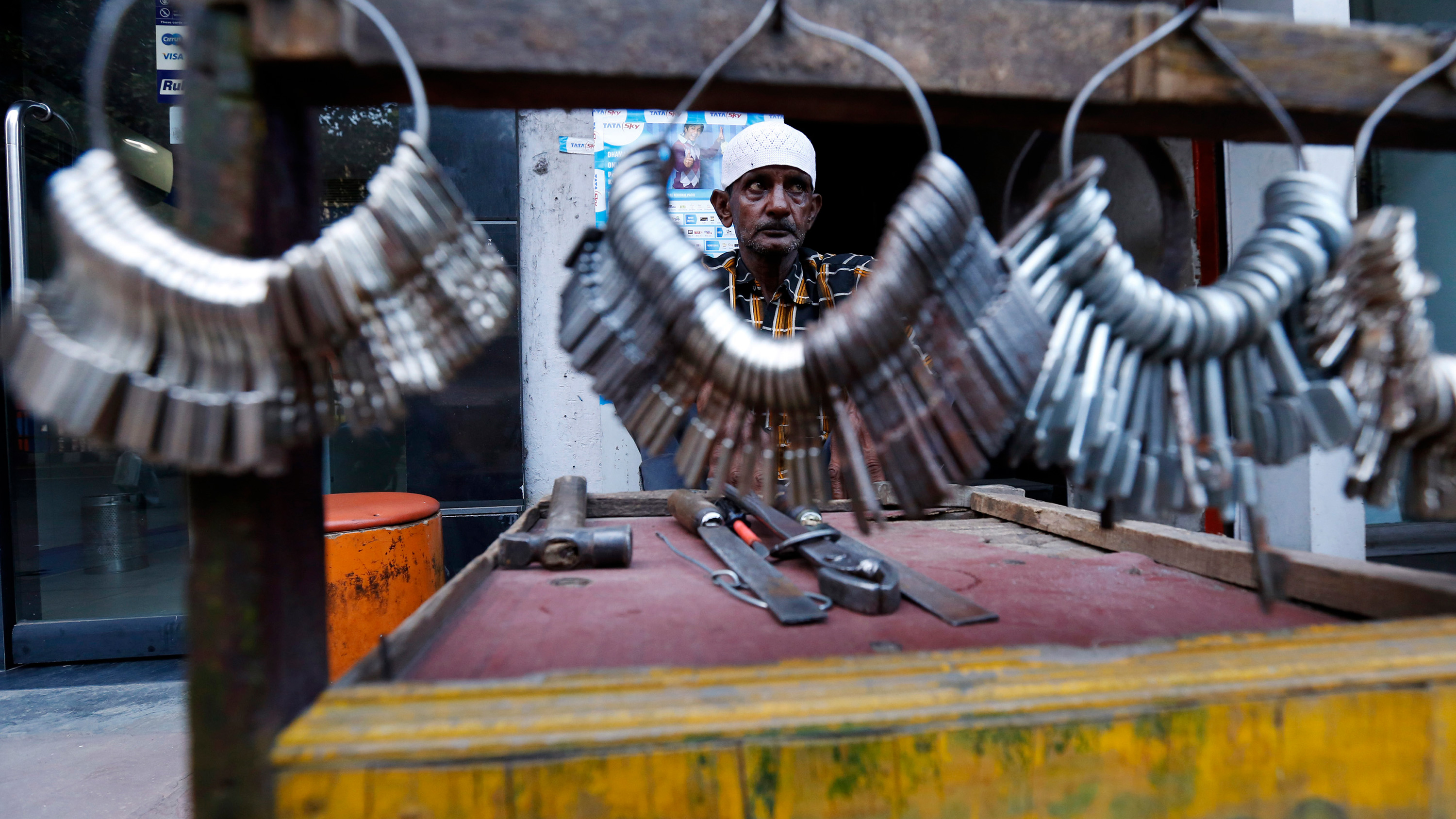 The photo shows a street vendor photographed through a large ring of keys hanging on his stand.