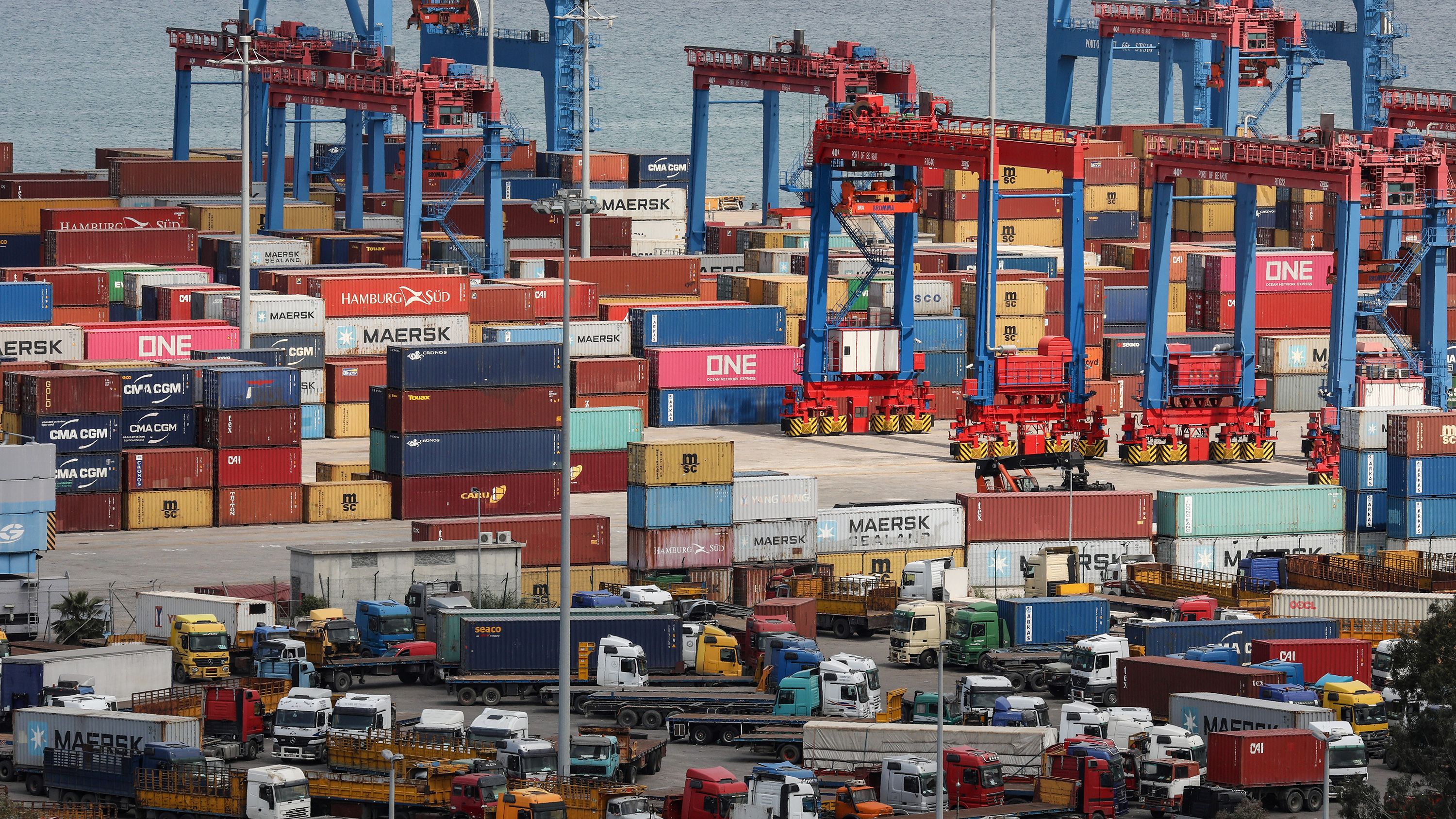 The photo shows an amazing pile of machines and metal containers stacked high, wall-to-wall in an overloaded industrial seaside dock.