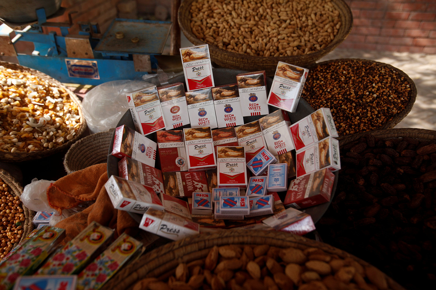 The photo shows a street stand with piles of nuts and mounds of smokes.