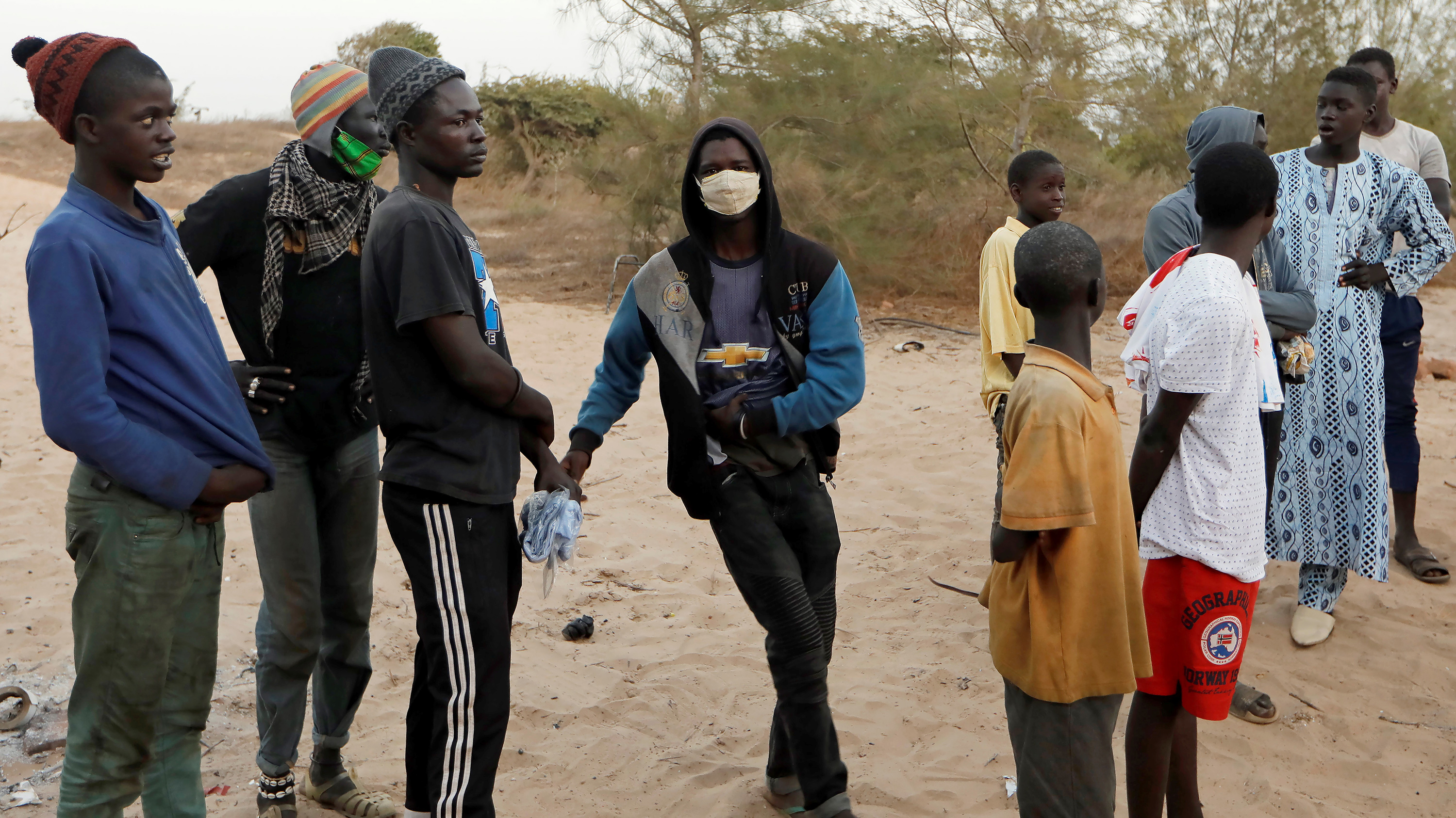 Picture shows a number of teenage boys standing around. One of them is wearing a mask.