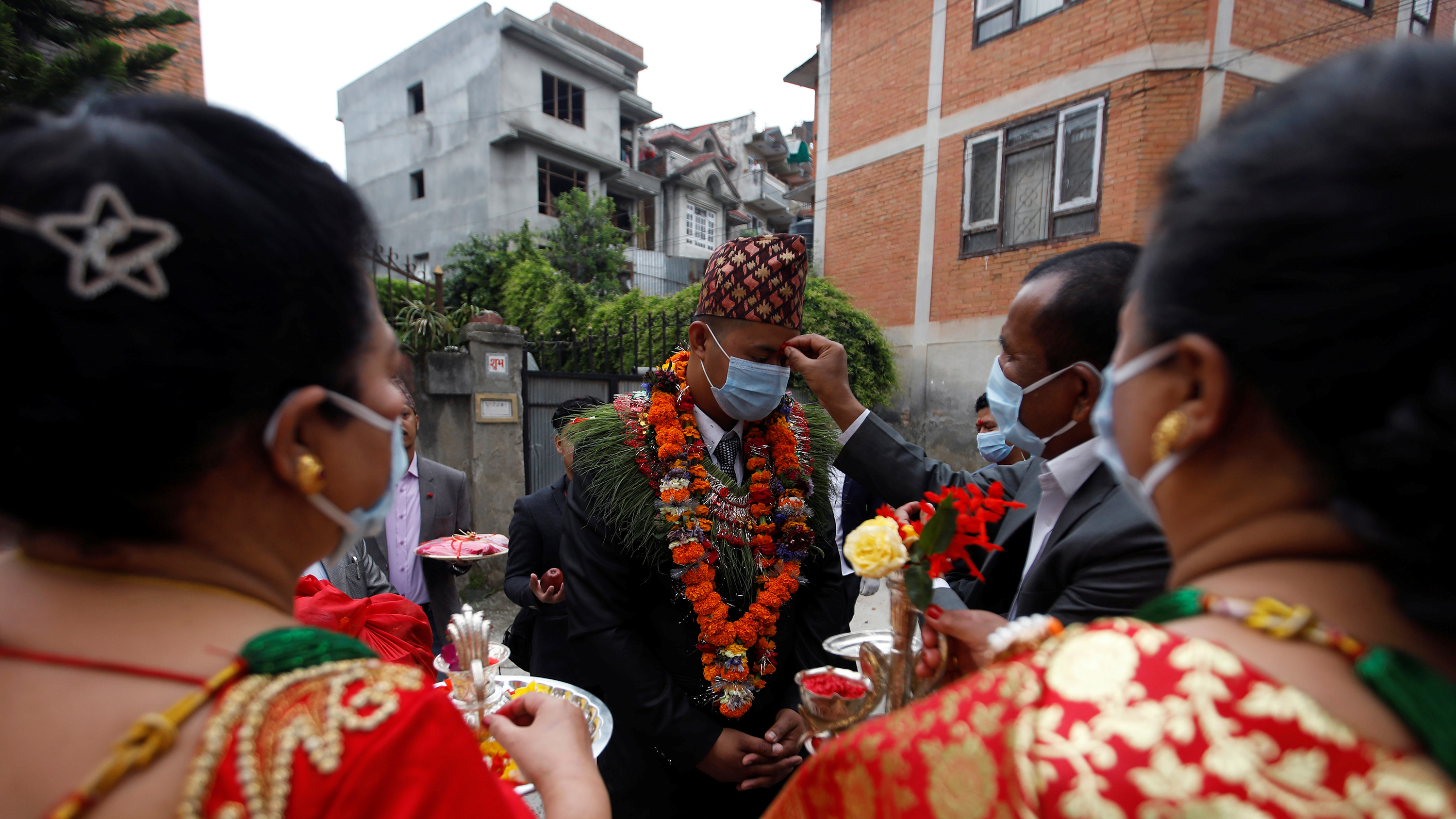 The photo shows the groom participating in the ceremony with an official touching his head.